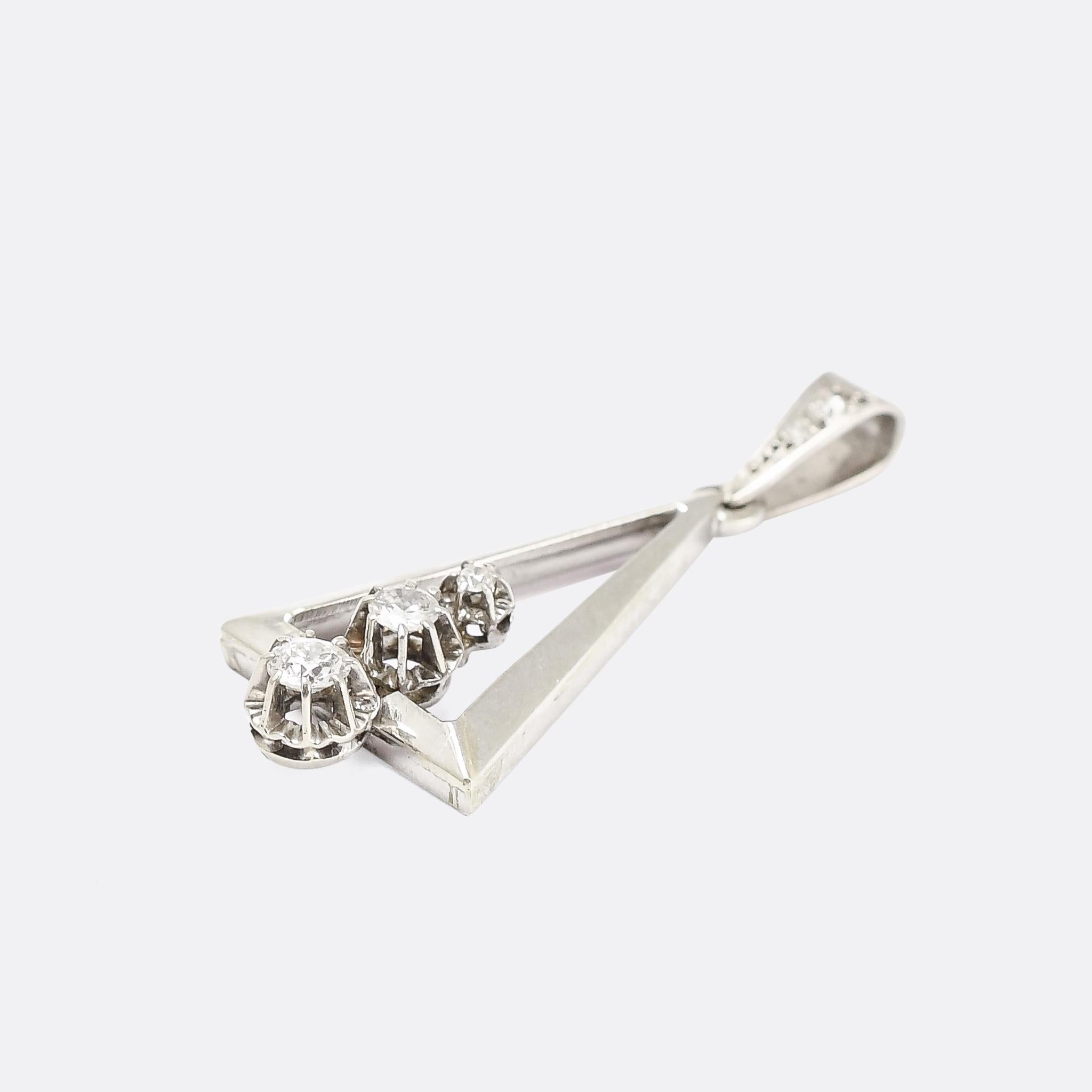 A striking Art Deco diamond pendant dating from the 1920s. It's French made, and crafted in 18k white gold throughout, with three graduated old European cut diamonds set on the short edge of an isosceles triangle. The long edges taper towards the