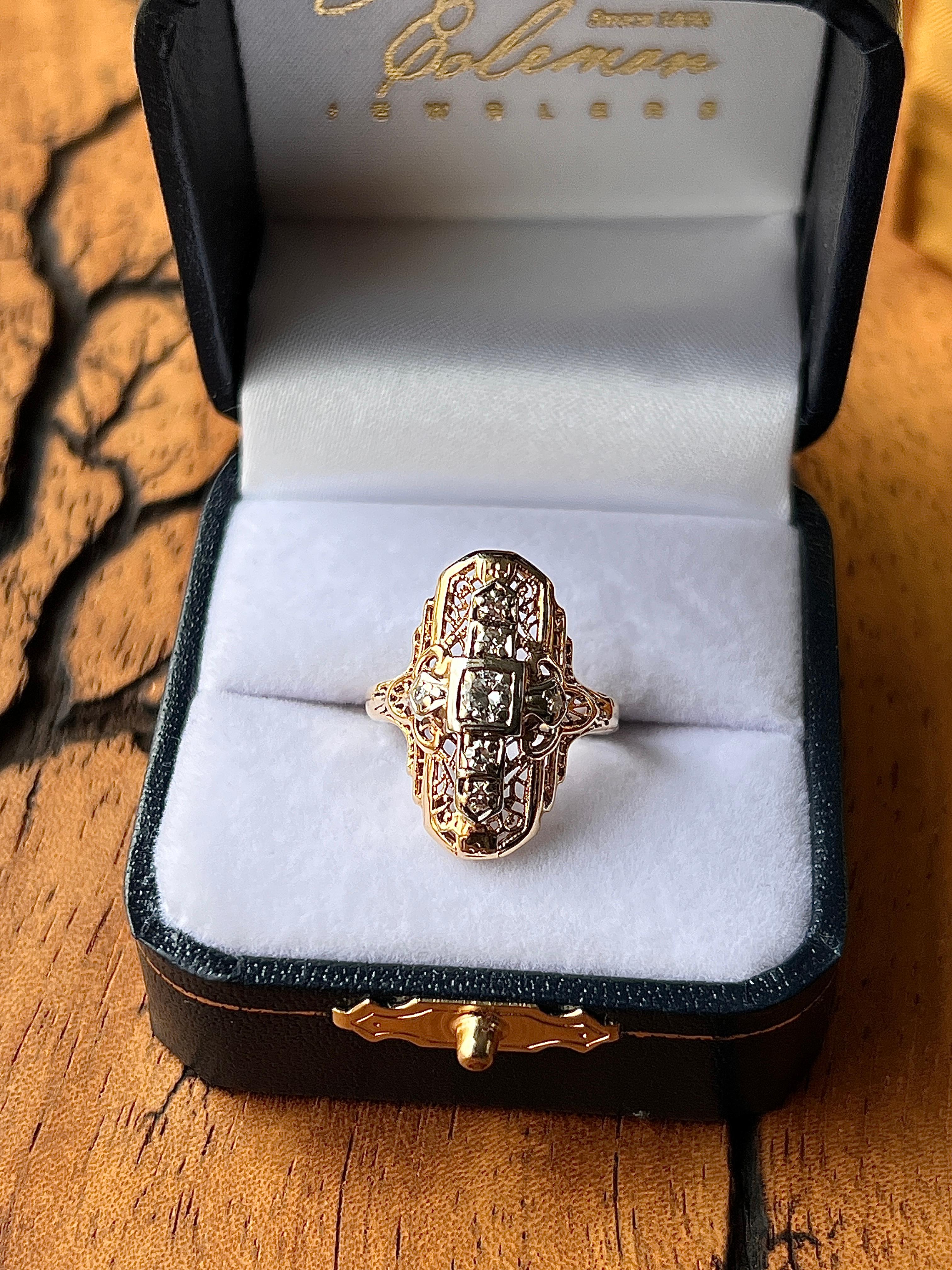 Ein Tafelring aus 14-karätigem Gelb- und Weißgold aus den 1930er Jahren, ein auffallendes Beispiel für die kühnen und doch komplizierten Designs der Art-déco-Ära. In seinem Zentrum ruht ein Diamant im alten europäischen Schliff von ca. 0,16 Karat