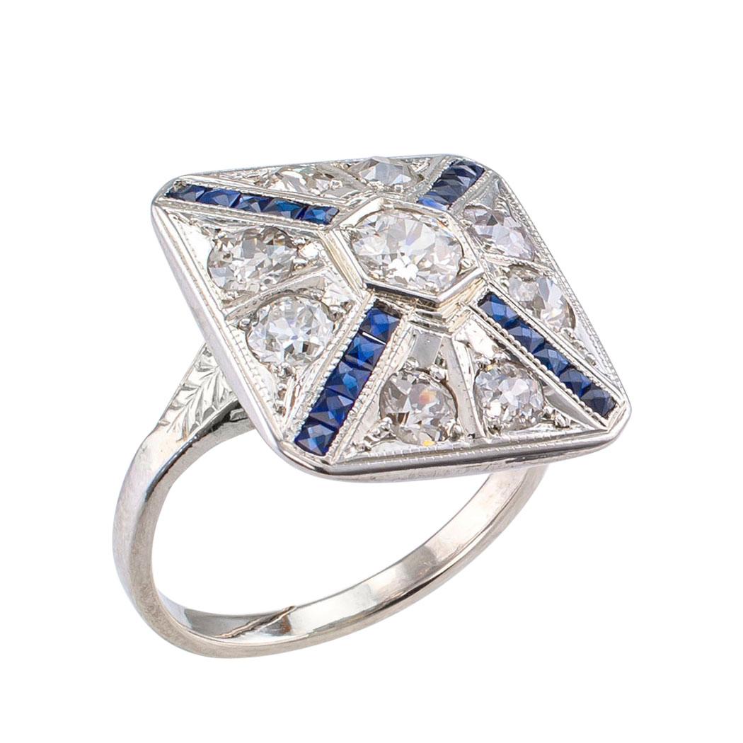 Art Deco diamond white gold dinner ring circa 1930. The slightly pyramid-shaped design centers upon an old European-cut diamond weighing approximately 0.25 carat, the pyramid’s corners set with French-cut simulated blue sapphires, original to the