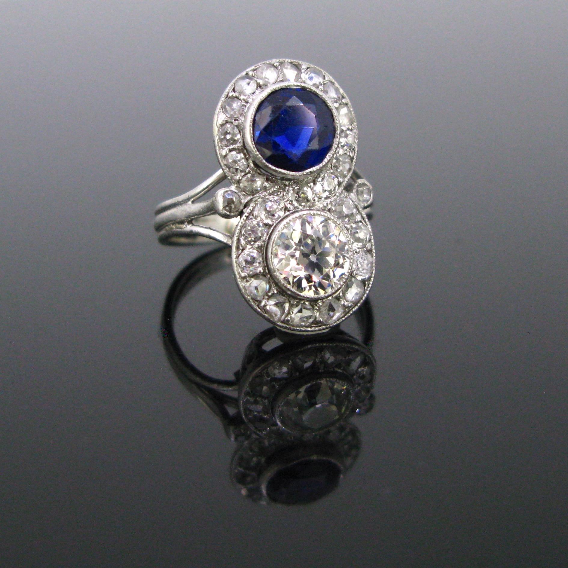 This beautiful ring comes directly from the Art Deco era. It features a round faceted sapphire weighing approx. 1ct and a diamond of around 0.70ct. Both the sapphire and the diamond are surrounded by 27 old cut diamonds forming a Toi et Moi design.