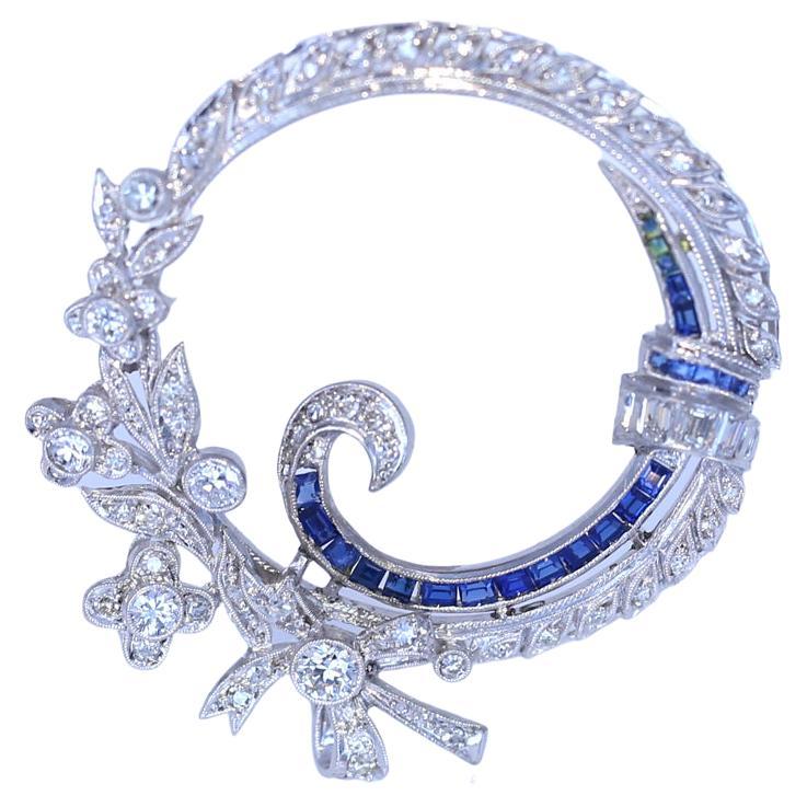 Art Deco style brooch with Diamonds and Sapphires. The inner circle is decorated with a row of Sapphires, ribbon-like. The outer circle is all flowers and Diamonds.
Once it was common to communicate a message via pin or brooch. Nowadays this art is