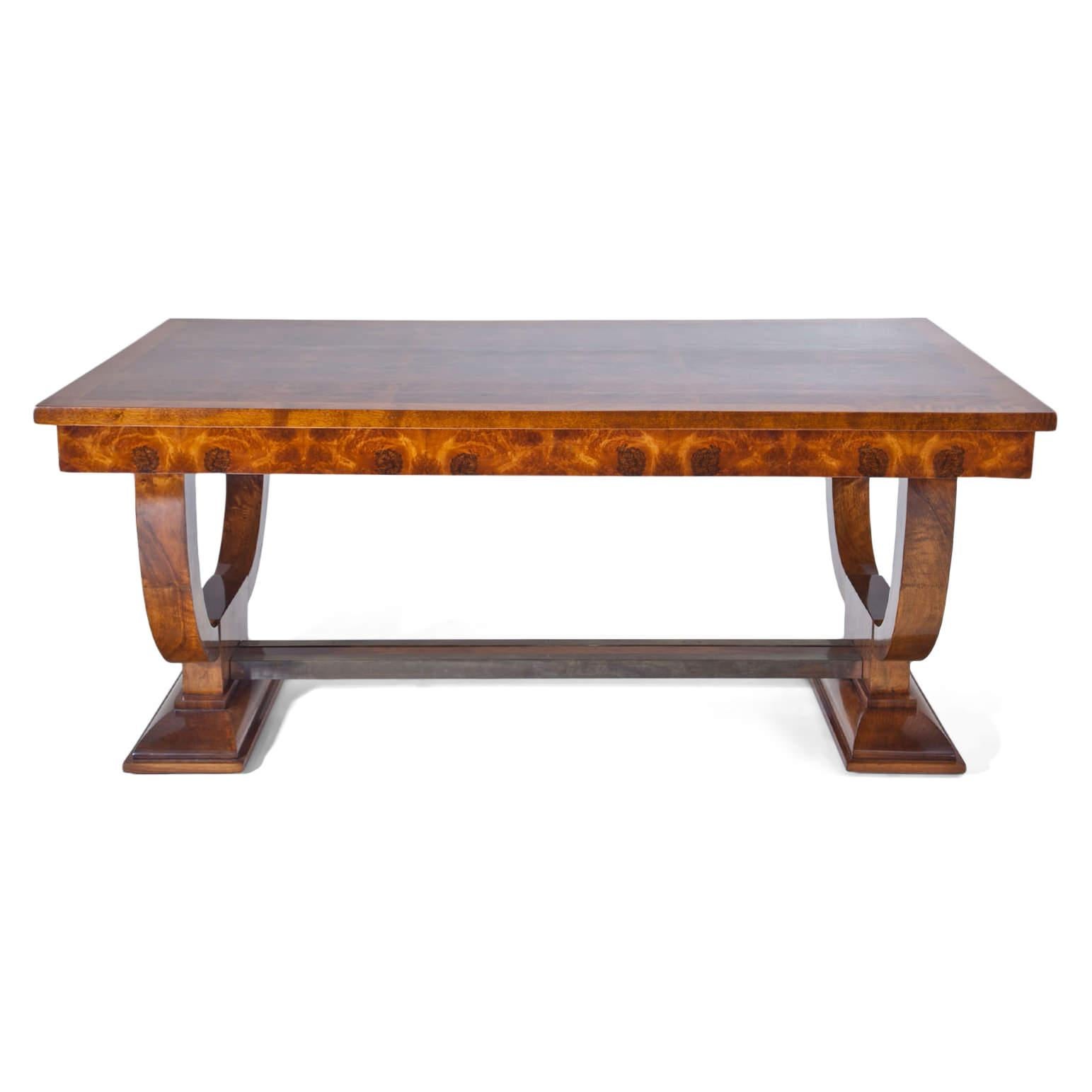 Large dining room table with eight fitting chairs of the Art Deco. The table with burl wood veneer and u-shaped legs and a metal-reinforced strutting. The table can be extended on both sides. The chairs show mirrored burl wood veneer on the