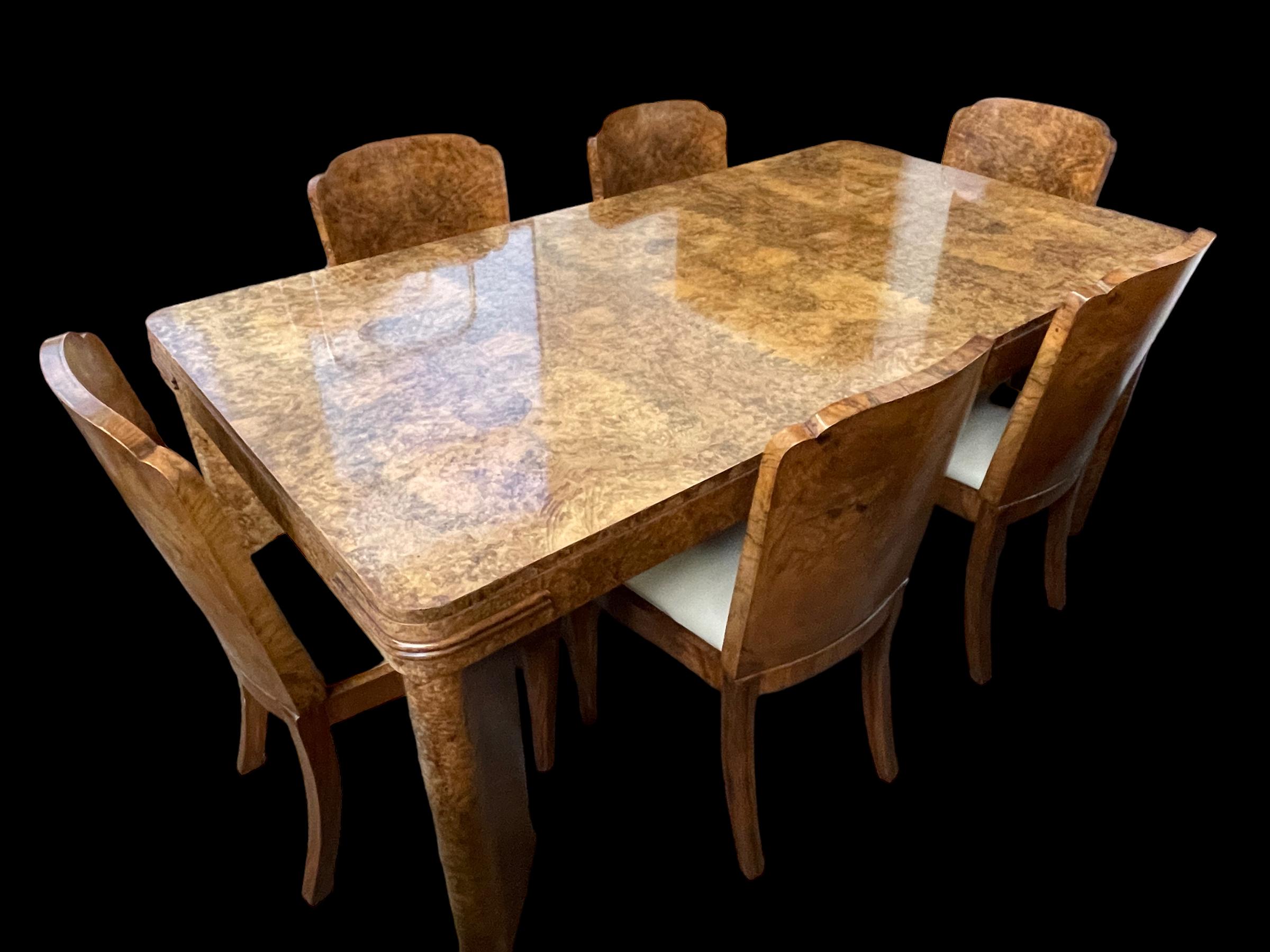 A fine Art Deco Maurice Adams dining room table and six chairs. In walnut with well designed slanted legs to the table with banding to each of the four table top corners. The matching chairs in walnut and the seats just reupholstered in soft cream