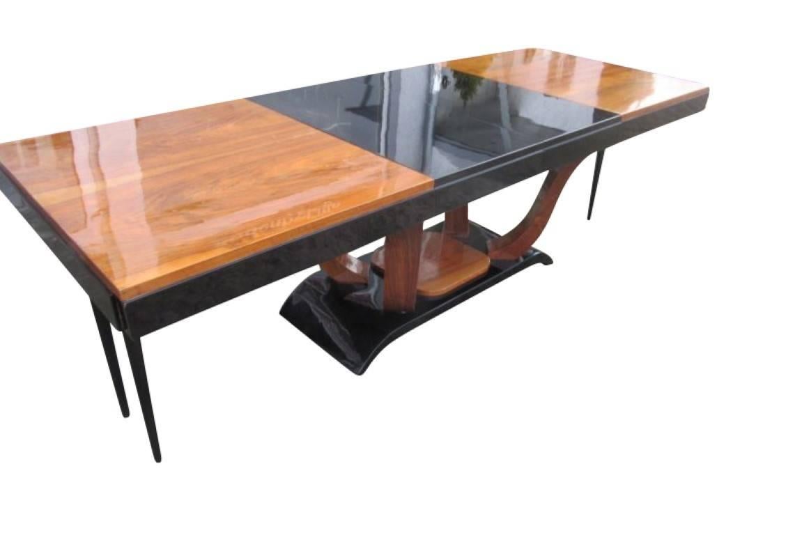 An original dining table of the Art Deco era from circa 1920. The plate is of walnut wood veneer and was lacquered and polished to high gloss. Two removable, black lacquered insert plates extend the top to about 238 centimeters. The bottom of the