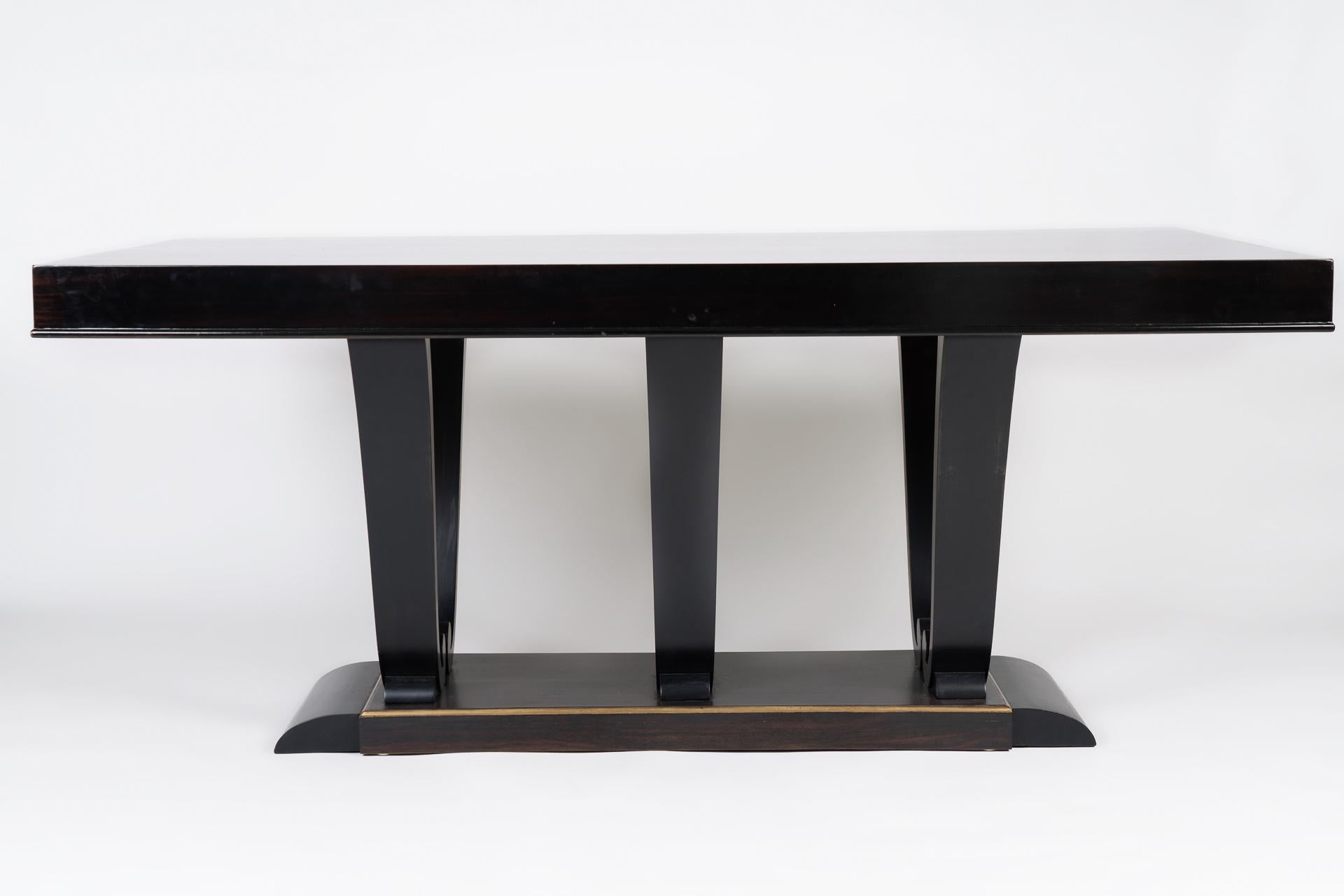 This dining table takes its inspiration from the Art Deco designs of Jacques-Emile Ruhlmann. It combines the use of mahogany woods with gold detailing. The elegant shape and proportions of the table, along with the excellence in craftsmanship, make
