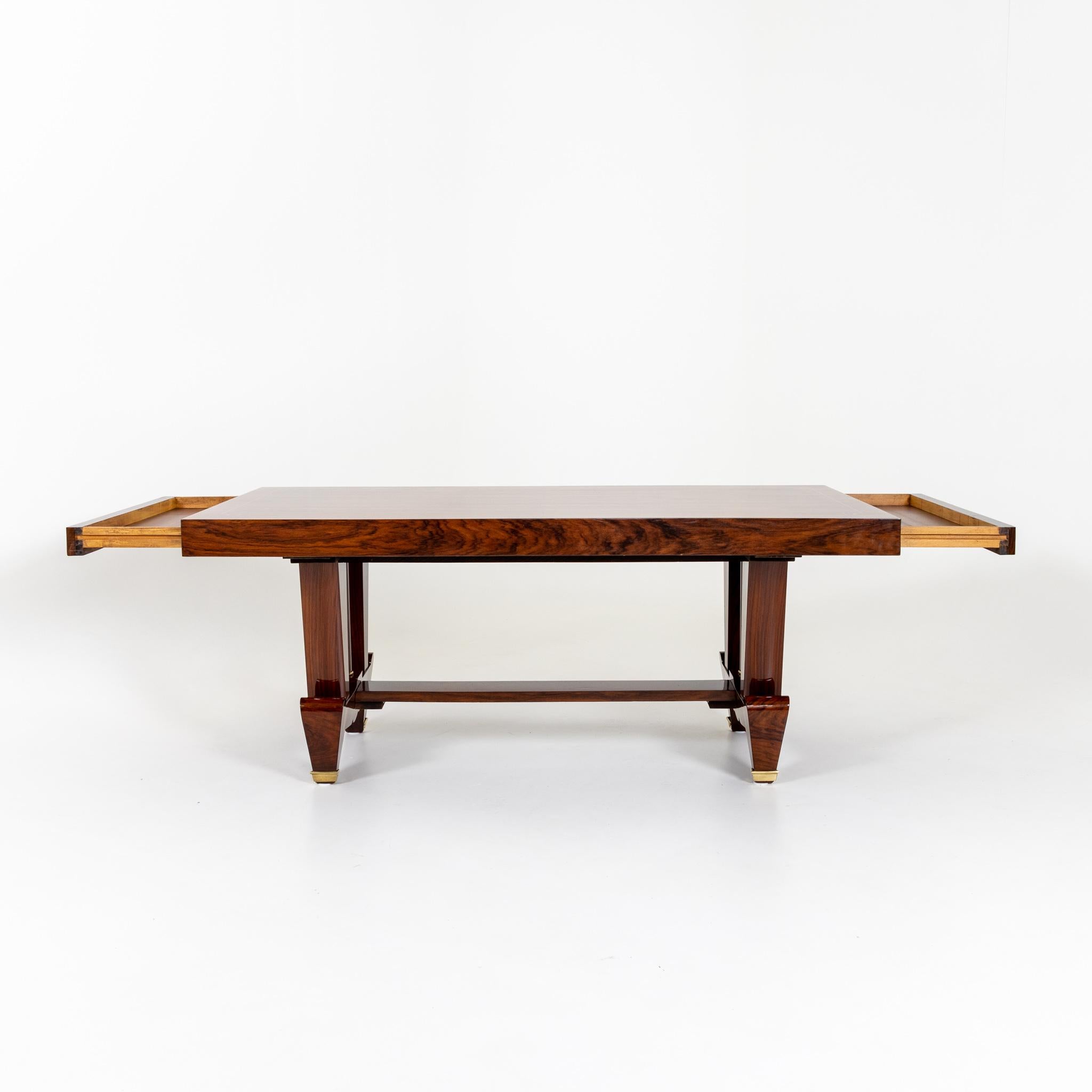 Art Deco table with rectangular tabletop with large drawers on the narrow sides and unusual base with brass applications. The tabletop is framed with thread inlays. The table has been expertly restored and hand polished.