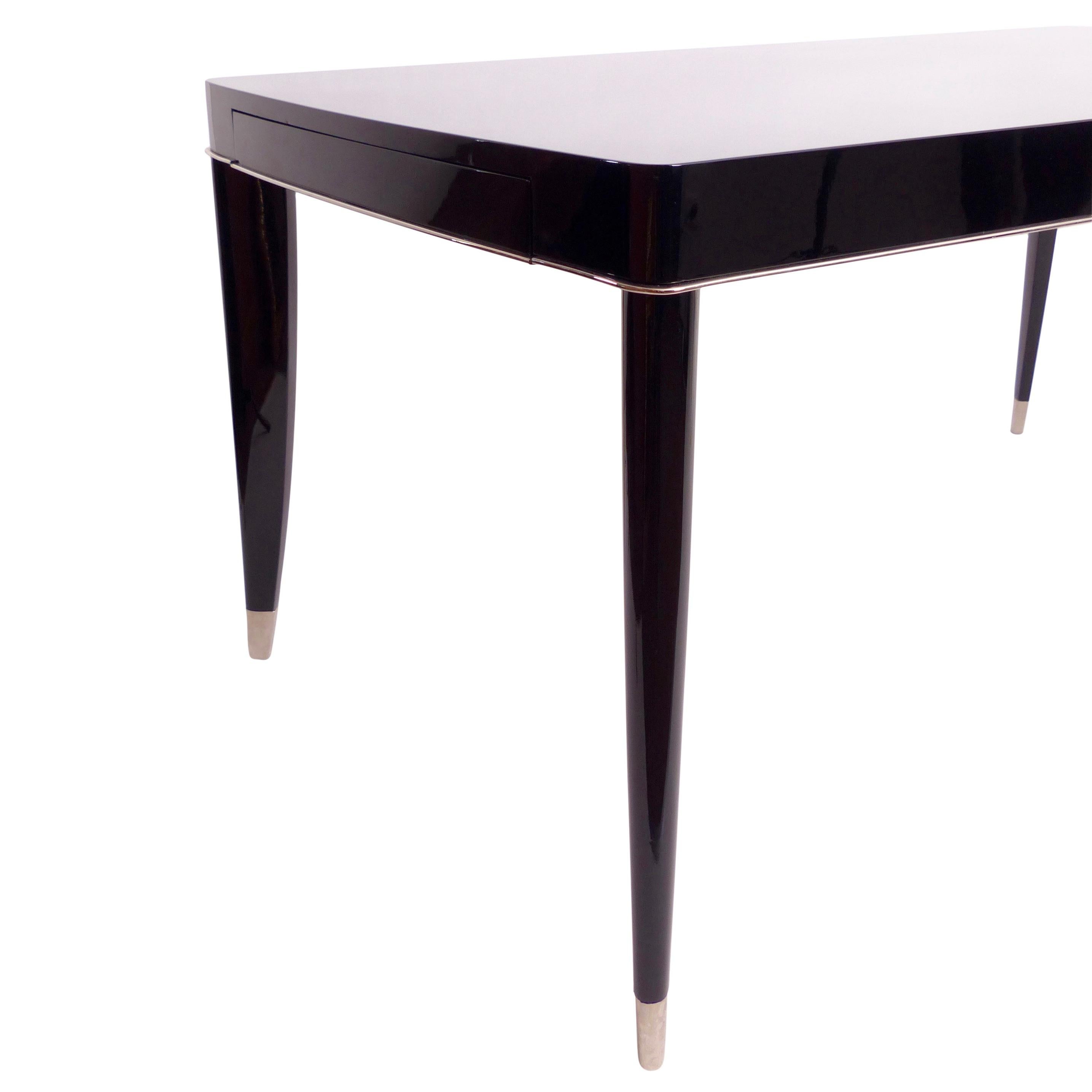 Dining table by the Belgian furniture manufacturer De Coene Frères
Balck high gloss lacquer
Original nickel-plated metal sabots on the legs
Original all-round metal band 
Extensions (new & black) 

Belgium 1940s

Dimensions:
Width: 165 cm
Height: 77