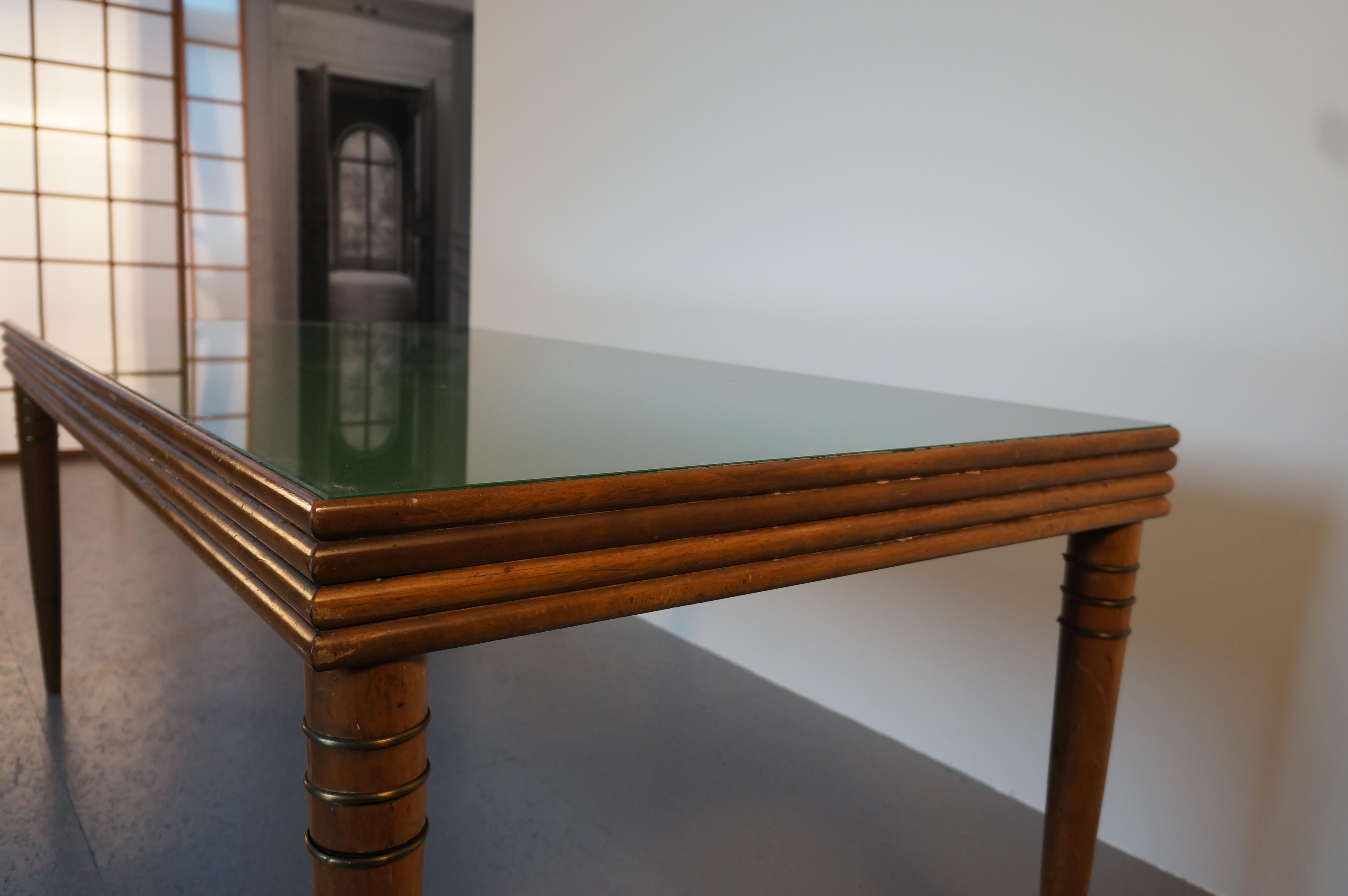 Vintage British racing green table with coned legs. On top a beautiful green glass plate surrounded by ridged wood frame. Its tapered legs are accented by brass rings.