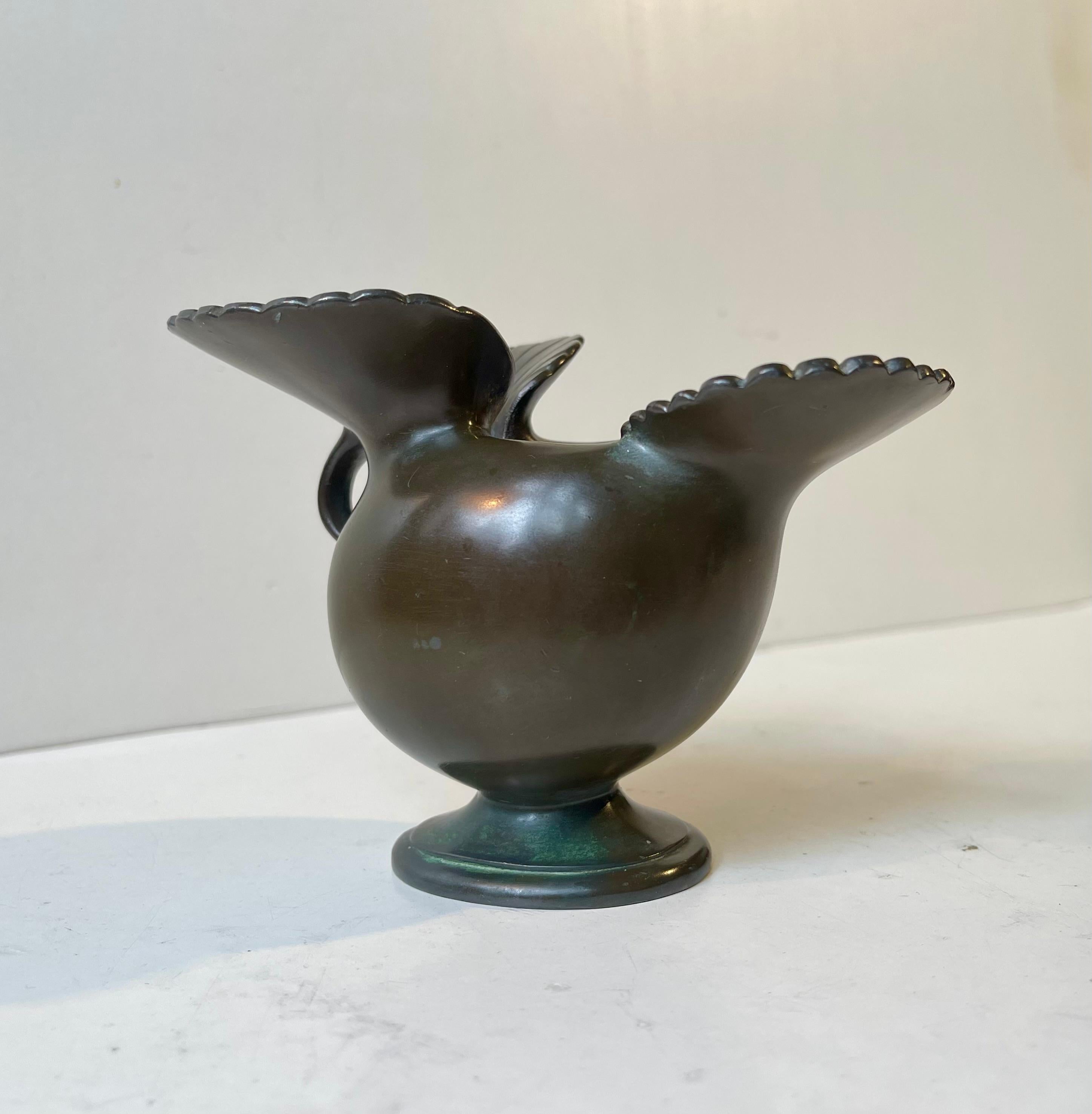 Insolito vaso a forma di gallina di Just Andersen disegnato intorno al 1930. È realizzato in diskometal, una lega di peltro e patina applicata che imita il bronzo. La forma a gallina ti permette di avere due piccole composizioni floreali. Uno per