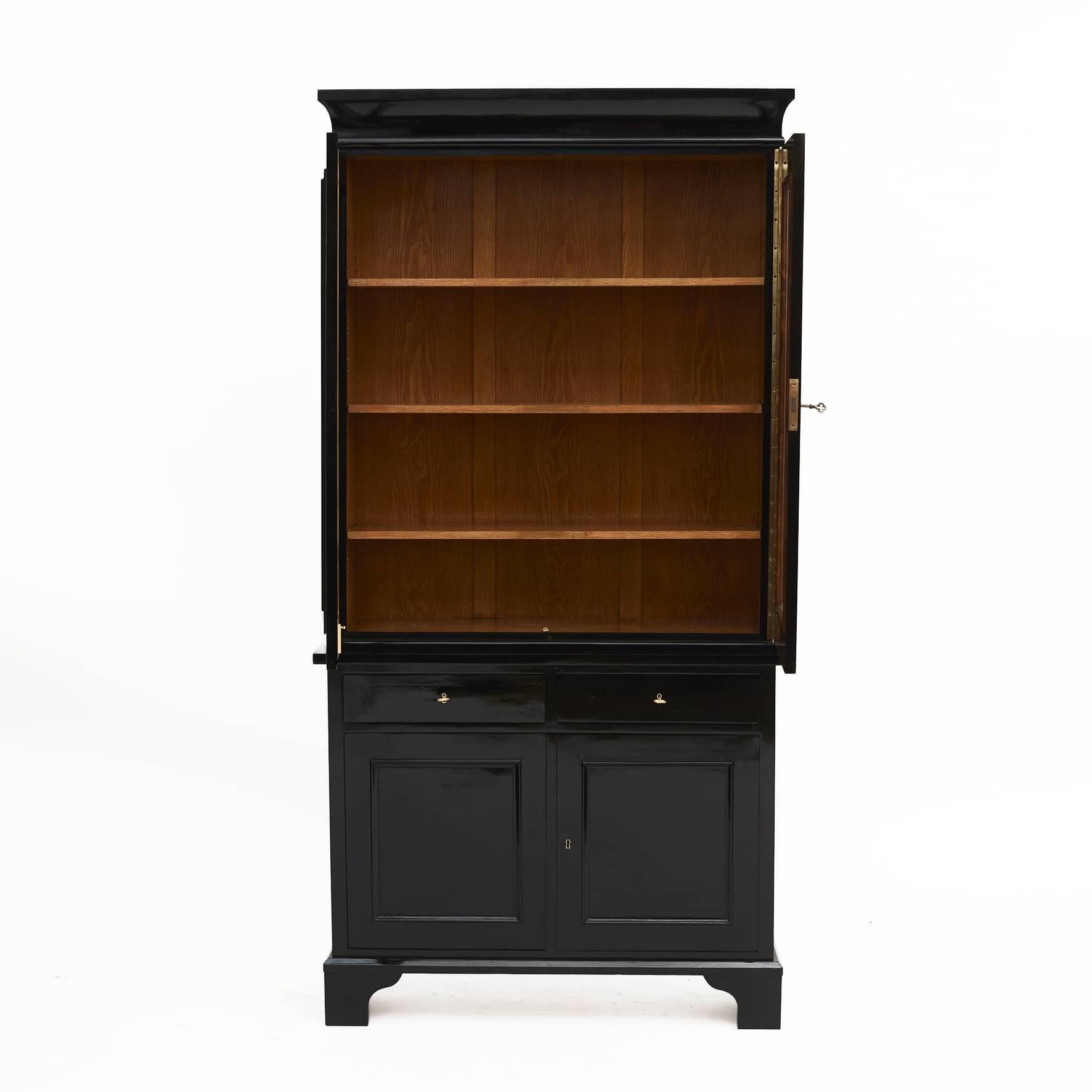 Art deco display cabinet, ebonized wood in 2 parts.
Upper part with pair of doors with faceted glass.
Underpart pair of doors with profiled fillings, above pair of drawers.
Denmark approx. 1920.
 