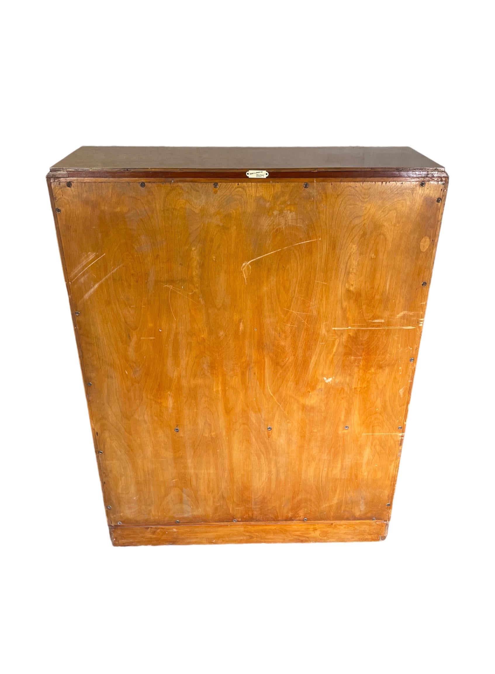 A very good quality Art Deco bookcase/cabinet in Birds Eye maple. Label to back shows maker - ‘Denby and Spinks Ltd. Albion Street, Leeds 1’. The two glazed doors with circular birdseye maple detailing, open to reveal three shelves, the top two