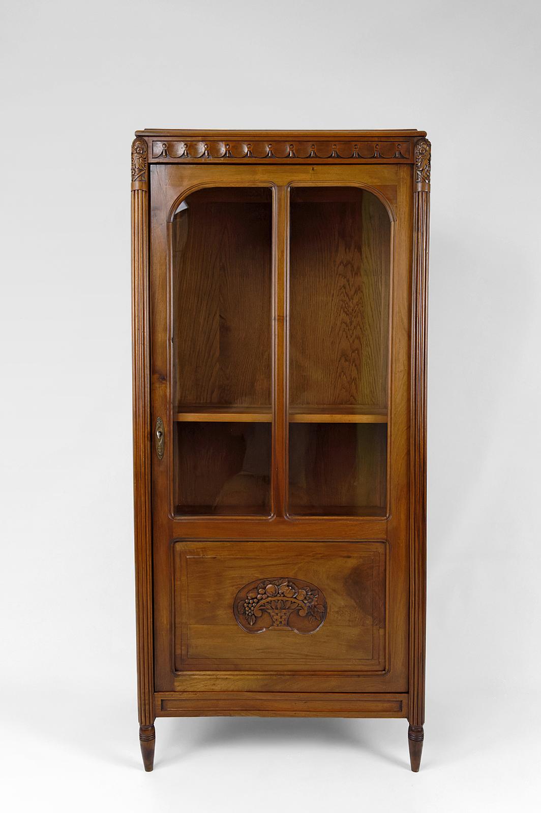 Cabinet / display case / bookcase with glass door, in walnut.

In the style of the productions of Follot, Dufrène.
Art Deco.
France, Circa 1920.

Carved fruit baskets on the door.
Pretty bronzes.
Fluted/tapered colonnades.

2 shelves.

Key + lock