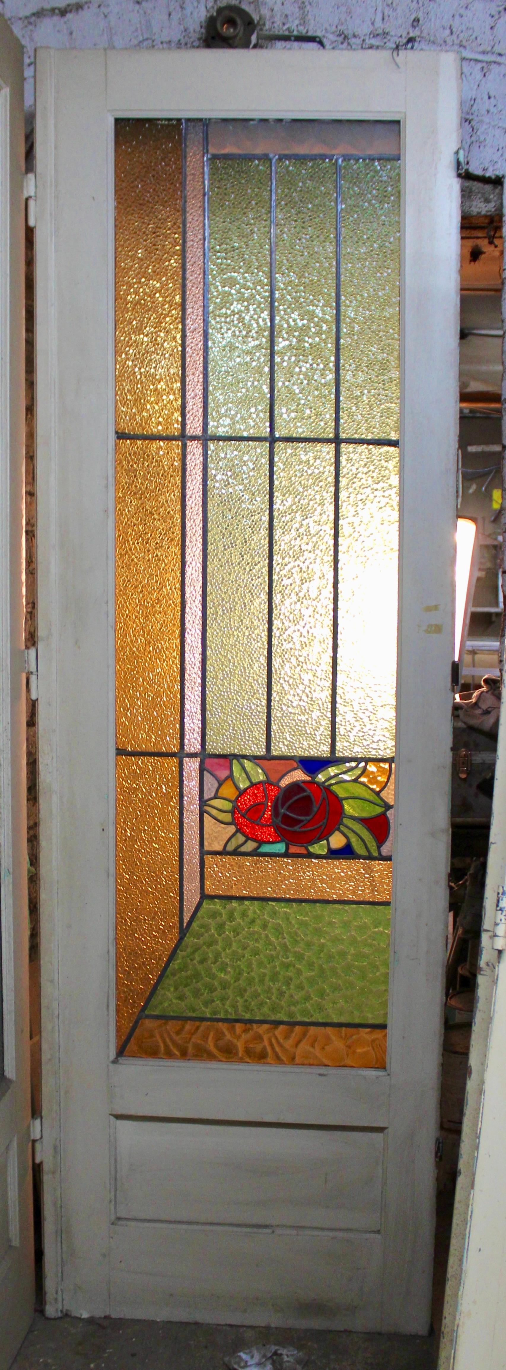 Porta alta con finestra in vetro colorato. Alta più di due metri e mezzo, con semplici disegni in piombo Art Déco e una coppia di rose.