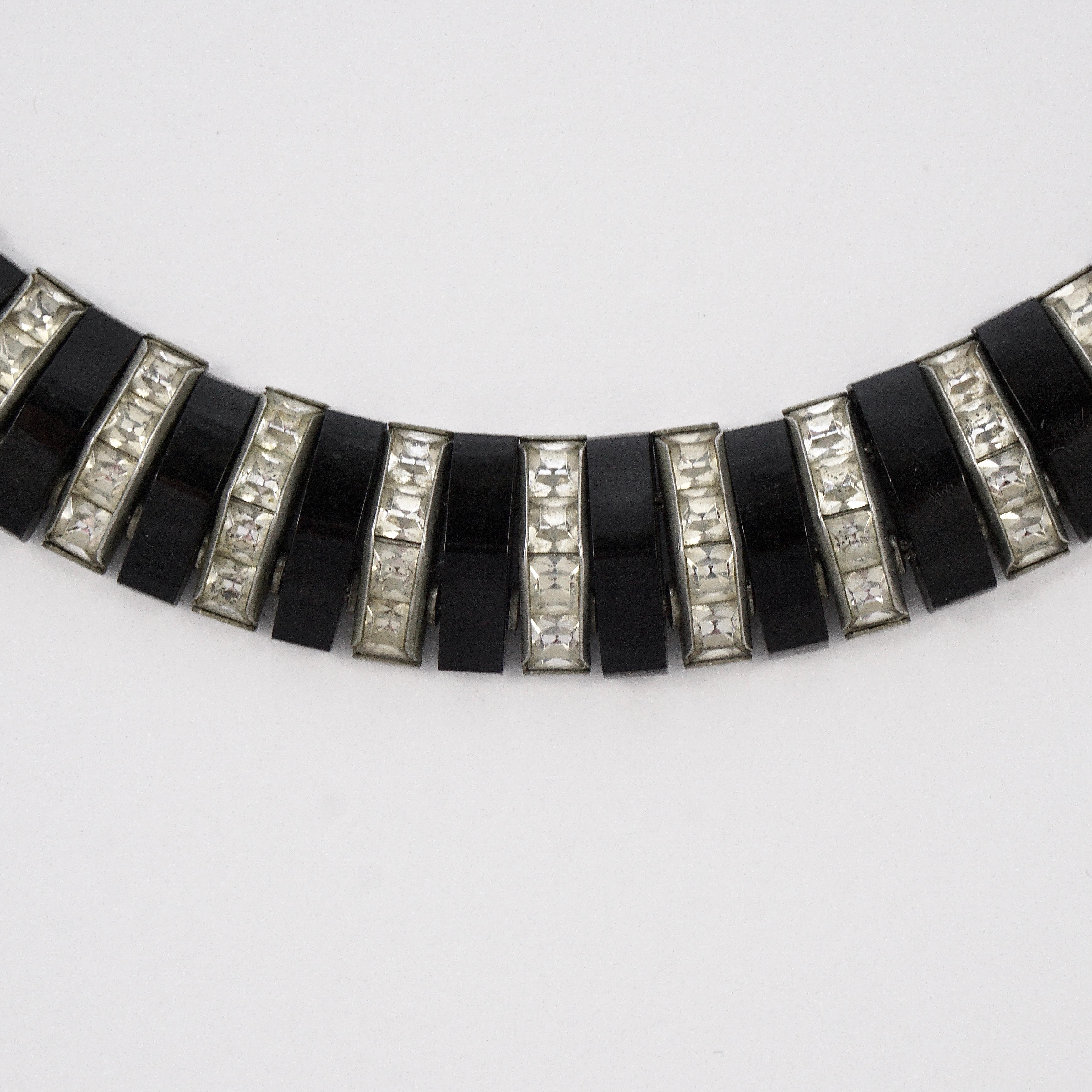 Fabulous silver tone original Art Deco necklace featuring channel set rhinestones and black bakelite. The rhinestones and black bakelite are separated by metal beads, to create the curve to go around the neck. The necklace has the German stamp DoSo,