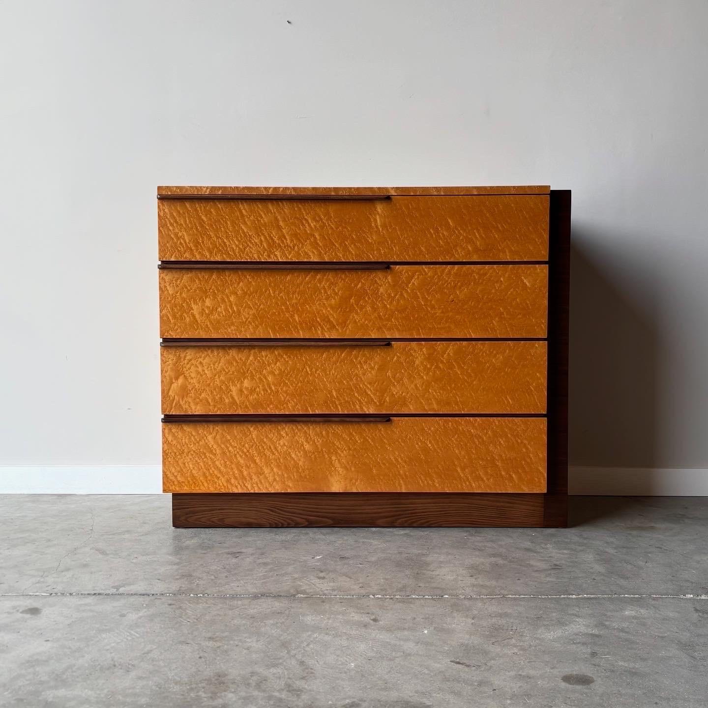 This stunning dresser showcases Gilbert Rohde's signature aesthetic, combining highly polished birds-eye maple with rich walnut construction. The piece brilliantly balances mid-century modern minimalism with the exquisite craftsmanship and premium