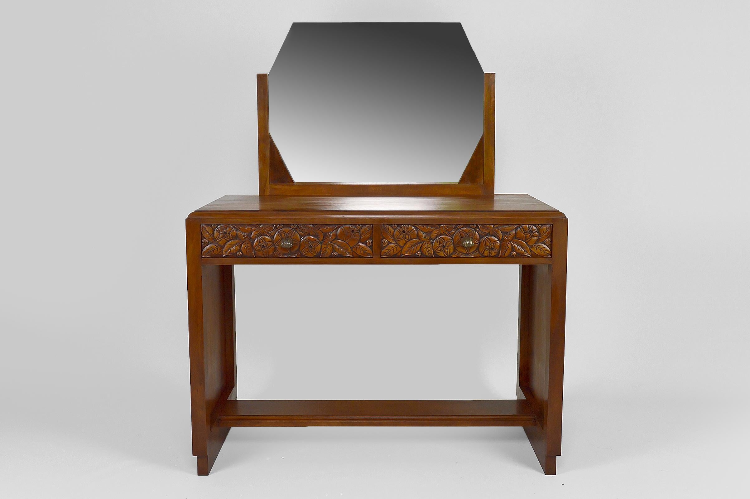 Elegant dressing / vanity table. 

Structure in walnut. 

2 drawers beautifully sculpted with flowers (stylized roses in the style of Charles Rennie Mackintosh) and beautiful silvered bronze handles.

Octagonal mirror, some marks.

Art Deco style,