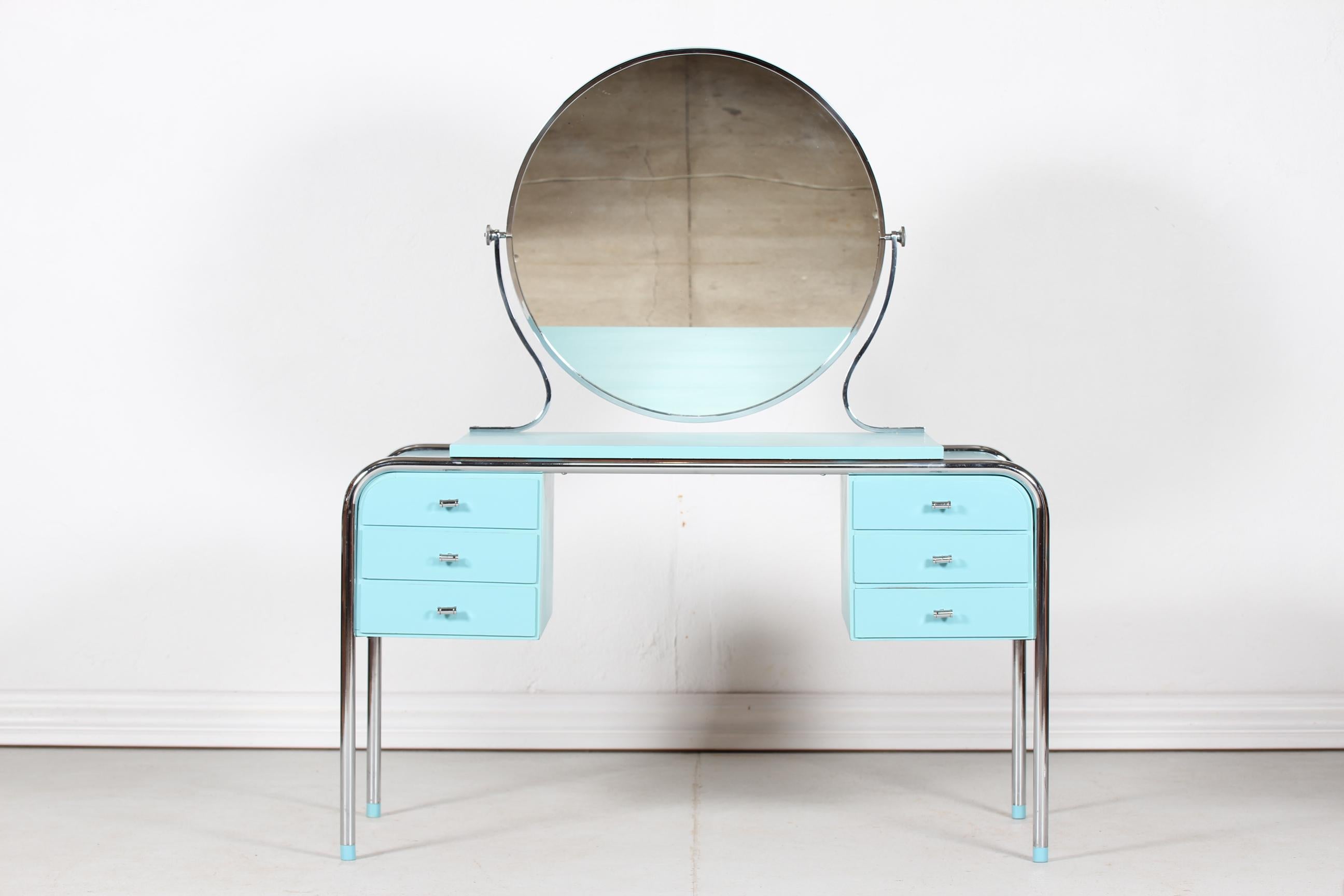 Danish Art Deco dressing table with 6 drawers, round tilt mirror and a matching chair manufactured by Danish cabinetmaker in the 1930´s.
The frame of the table, mirror and chair is of chromium-plated metal, the wooden parts is with turquoise paint