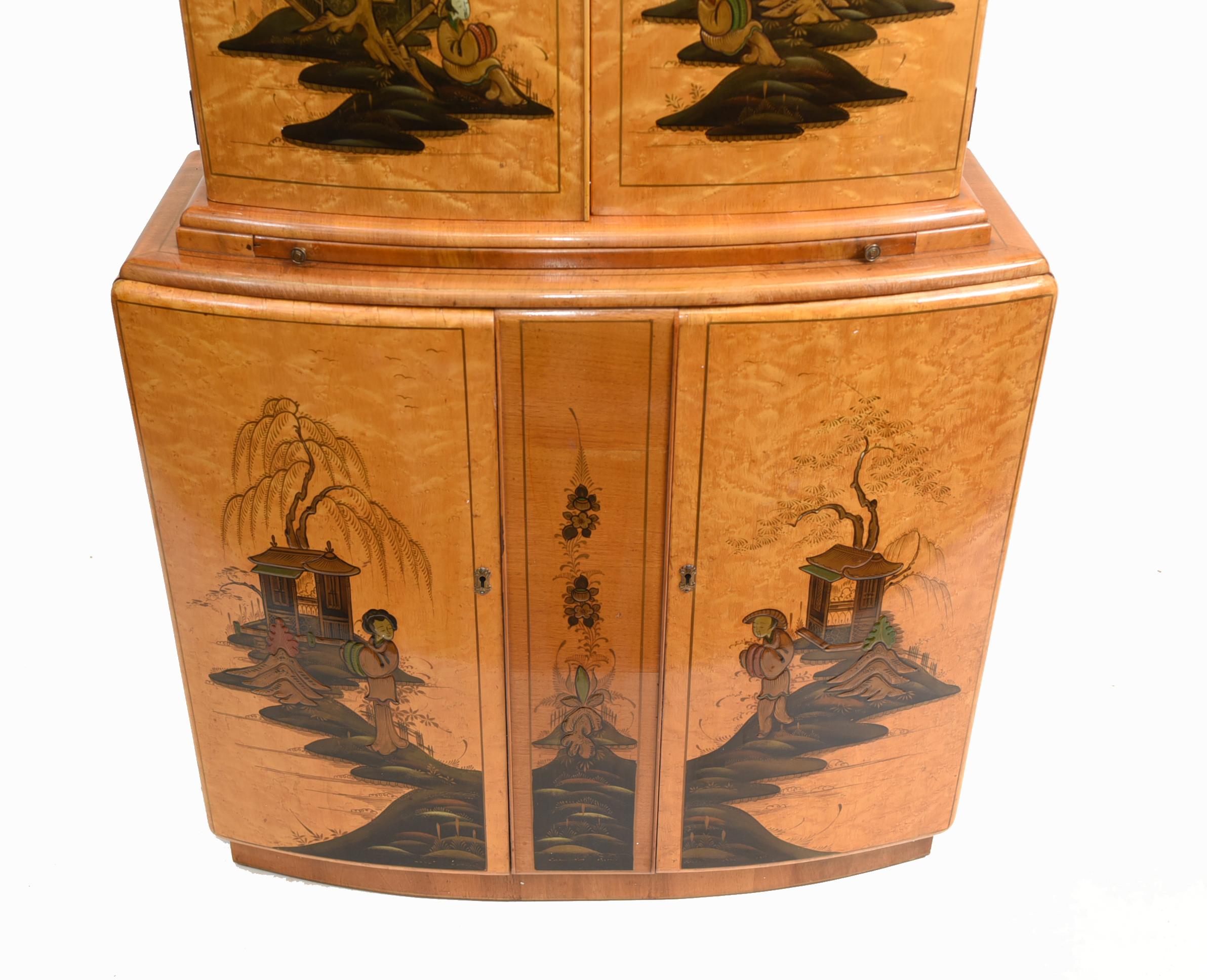 Wonderful period Art Deco drinks cabinet in satin birch
Features elegant Chionoiserie designs to the front showing various Chinese scenes and figures
Doors open out to reveal mirroed drink mixing and serving section to top
Original fixtures like