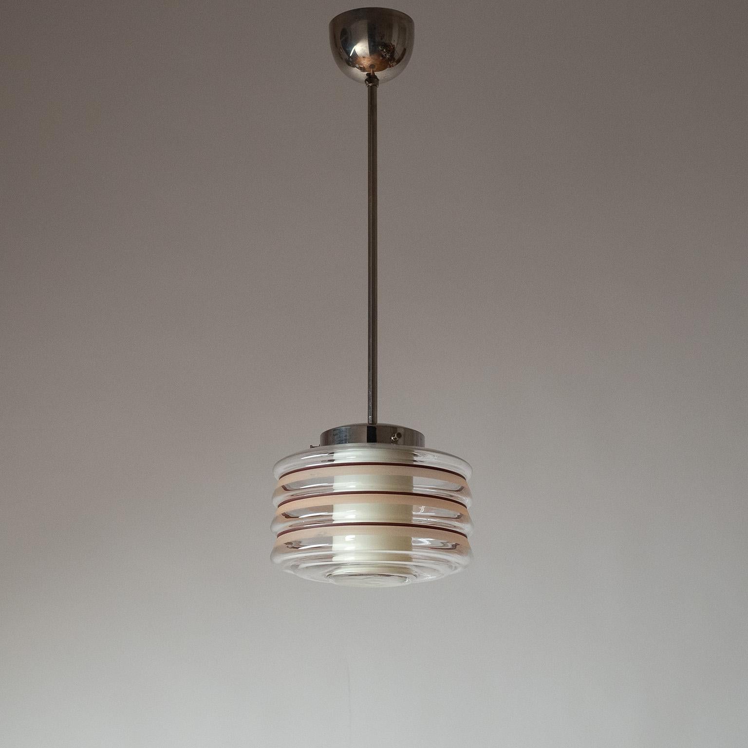 Pendente svedese a doppio vetro Art Déco degli anni 1930-1940. Il vetro esterno trasparente soffiato a coste con strisce dipinte a mano e il diffusore interno in vetro color avorio sono sostenuti da una ferramenta in nichel. Ottime condizioni
