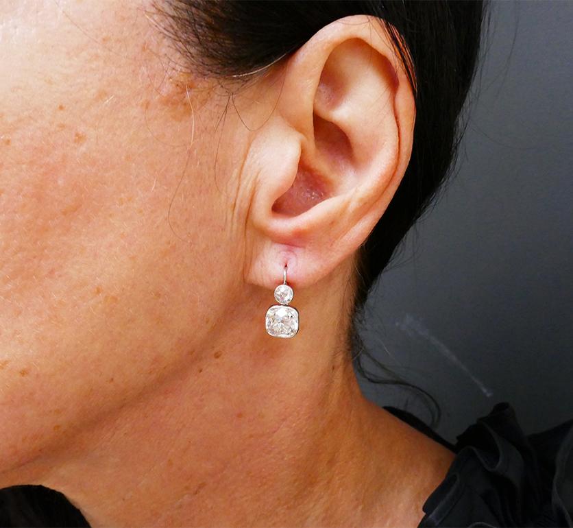 A pair of gorgeous Art Deco earrings made of platinum, featuring antique cut diamond. 
These diamond dangle earrings comprise two diamonds set one on top of another. The bottom diamond is a cushion cut and the top one is an Old European cut. This