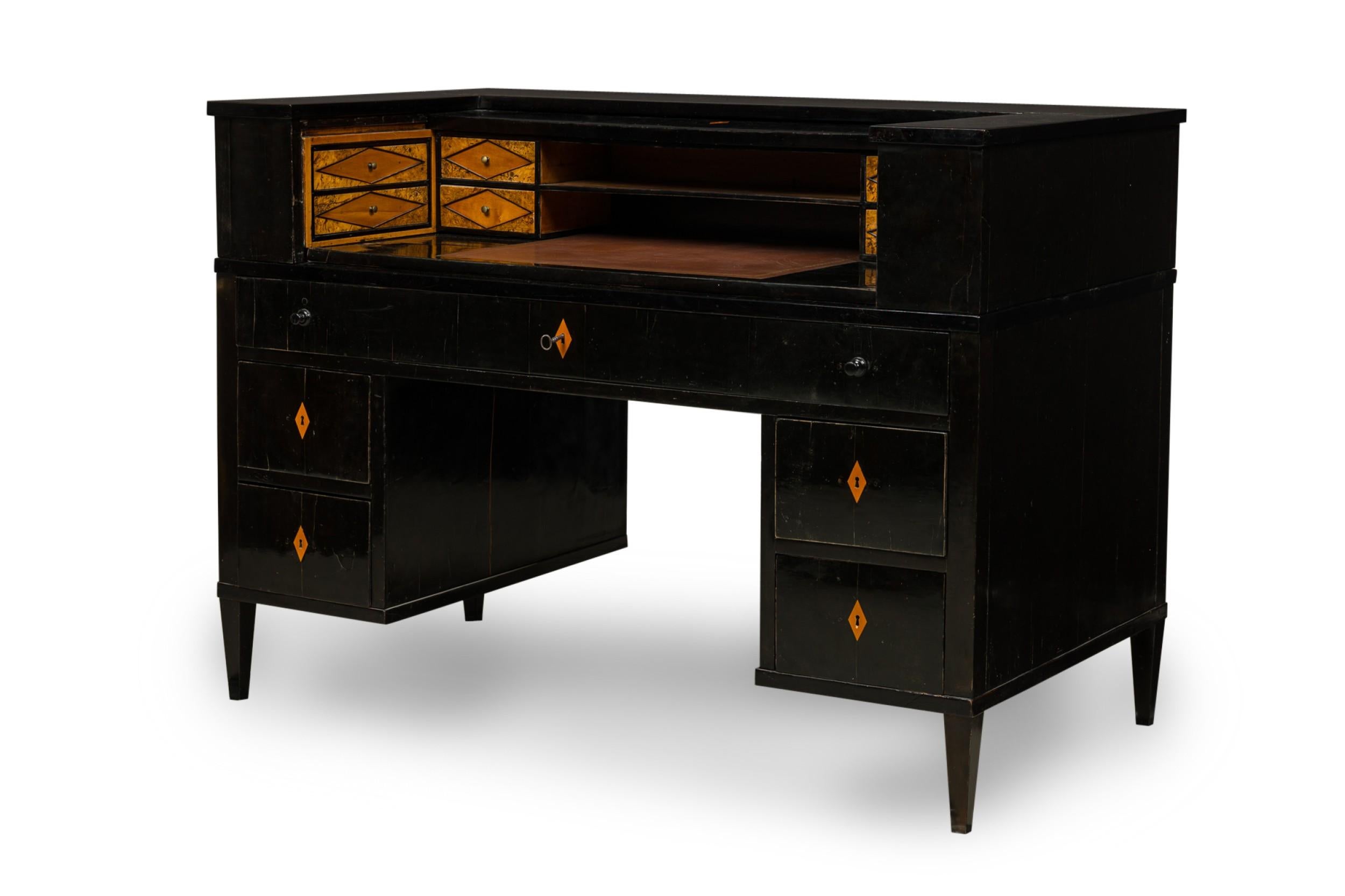 Art Deco ebonized pearwood writing desk with a tambour roll top upper section concealing four pairs of interior drawers with diamond pattern inlaid burl wood fronts surrounding a brown leather writing surface with a gilt embossed edge above a single