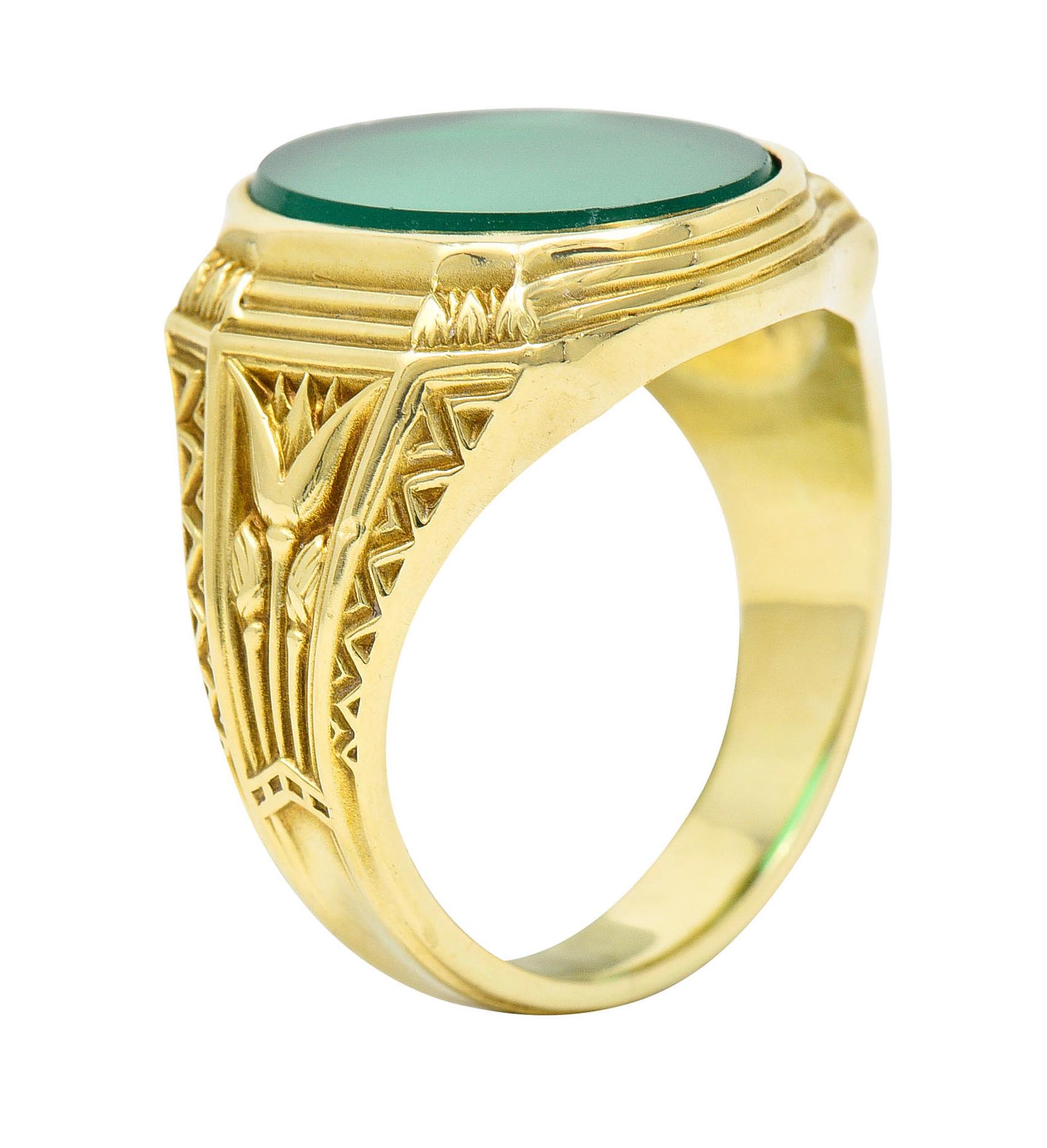 Signet style ring centers an oval tablet of chrysoprase measuring approximately 15.3 x 11.3 mm

Bezel set, translucent, and with uniform apple green color

With a deeply ridged surround and highly stylized lotus shoulders

With maker's mark and