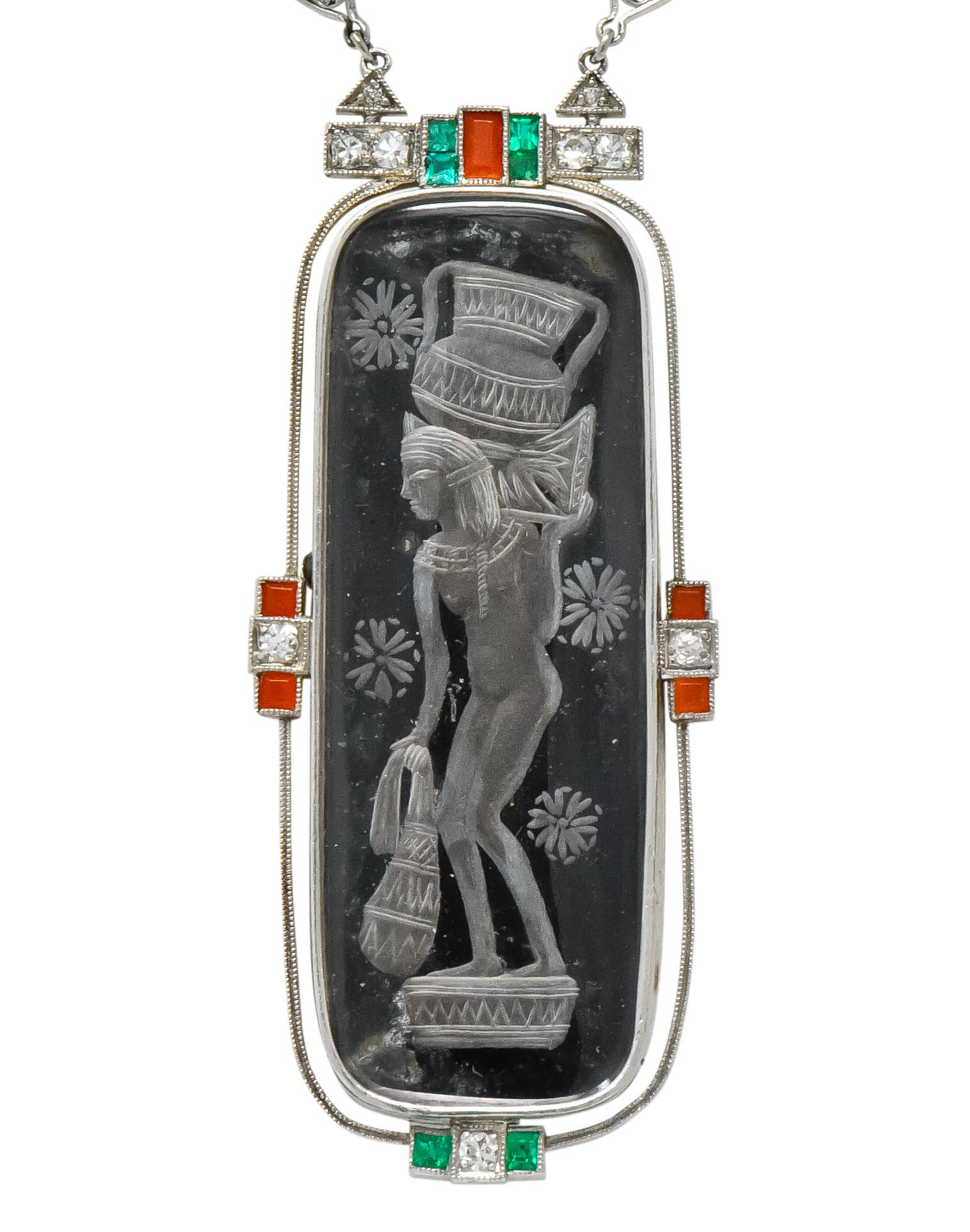 Art Deco platinum necklace featuring a fine Egyptian revival pendant

Pendant composed of a  reverse carved crystal, accented by diamonds, emeralds & coral

Chain set with eye clean and white old European cut diamonds

Unique clasp decorated with