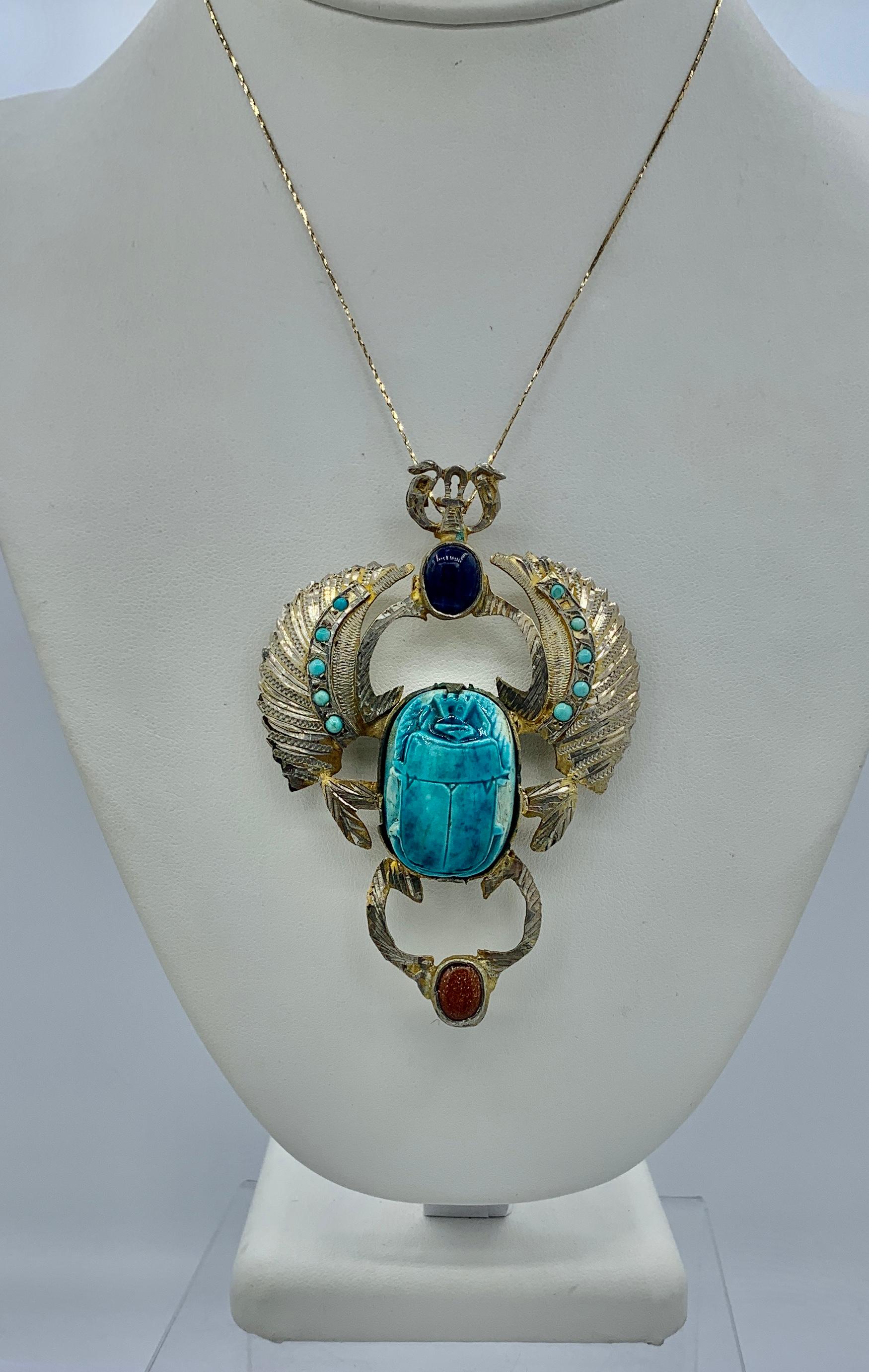 This is a very rare antique Art Deco Egyptian Revival Scarab Pendant or Brooch in Silver with a magnificent Turquoise Blue Faience Scarab with Turquoise adorned wings and Lapis Lazuli and Goldstone gems.  The antique jewel is of a monumental size