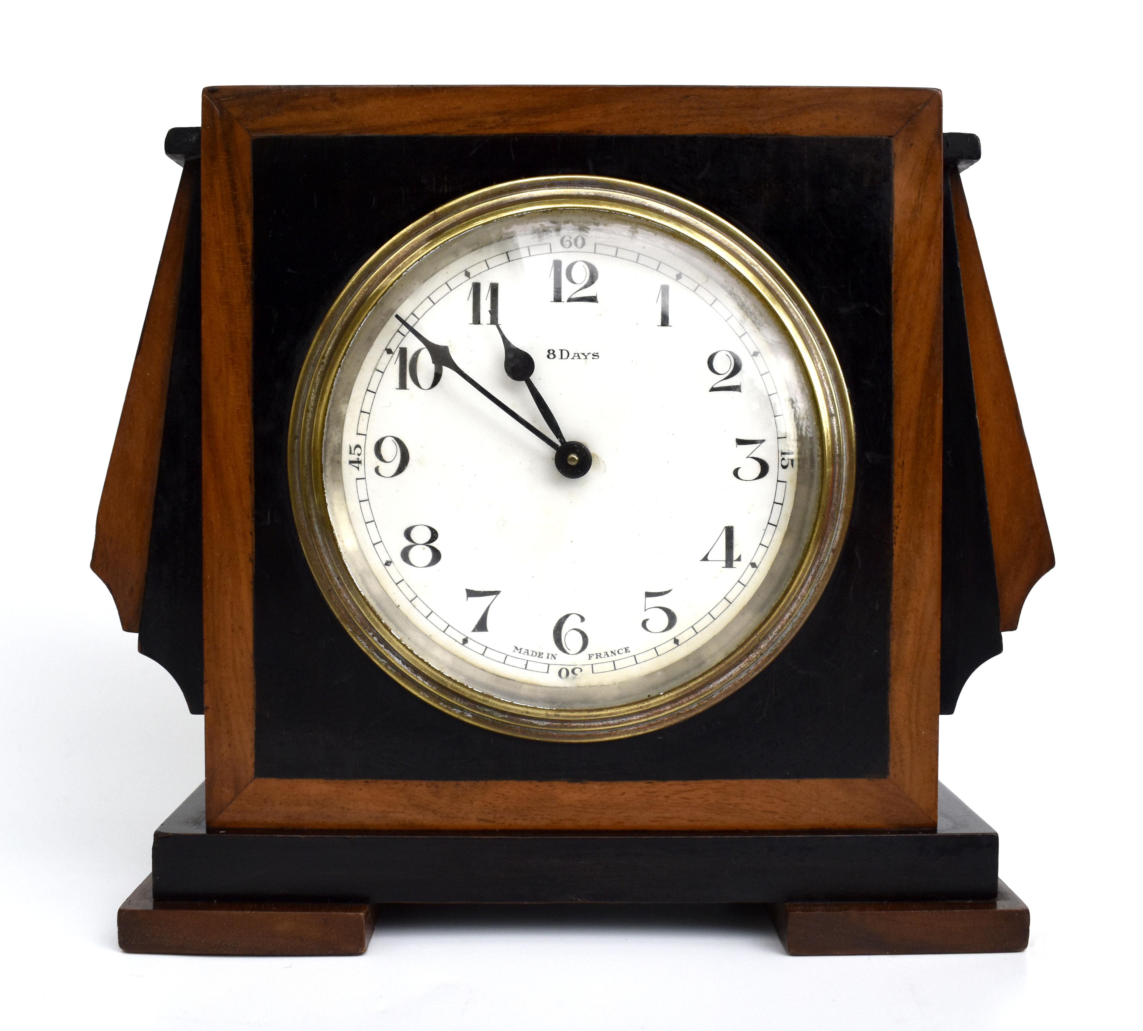 Rather stylish wooden 8 day mantle clock dating to the 1930's and French in origin. The white enamel dial is set within a brass chapter ring which in turn is frame in a two tone of Mahogany and ebonised casing. The protruding stepped fins to the