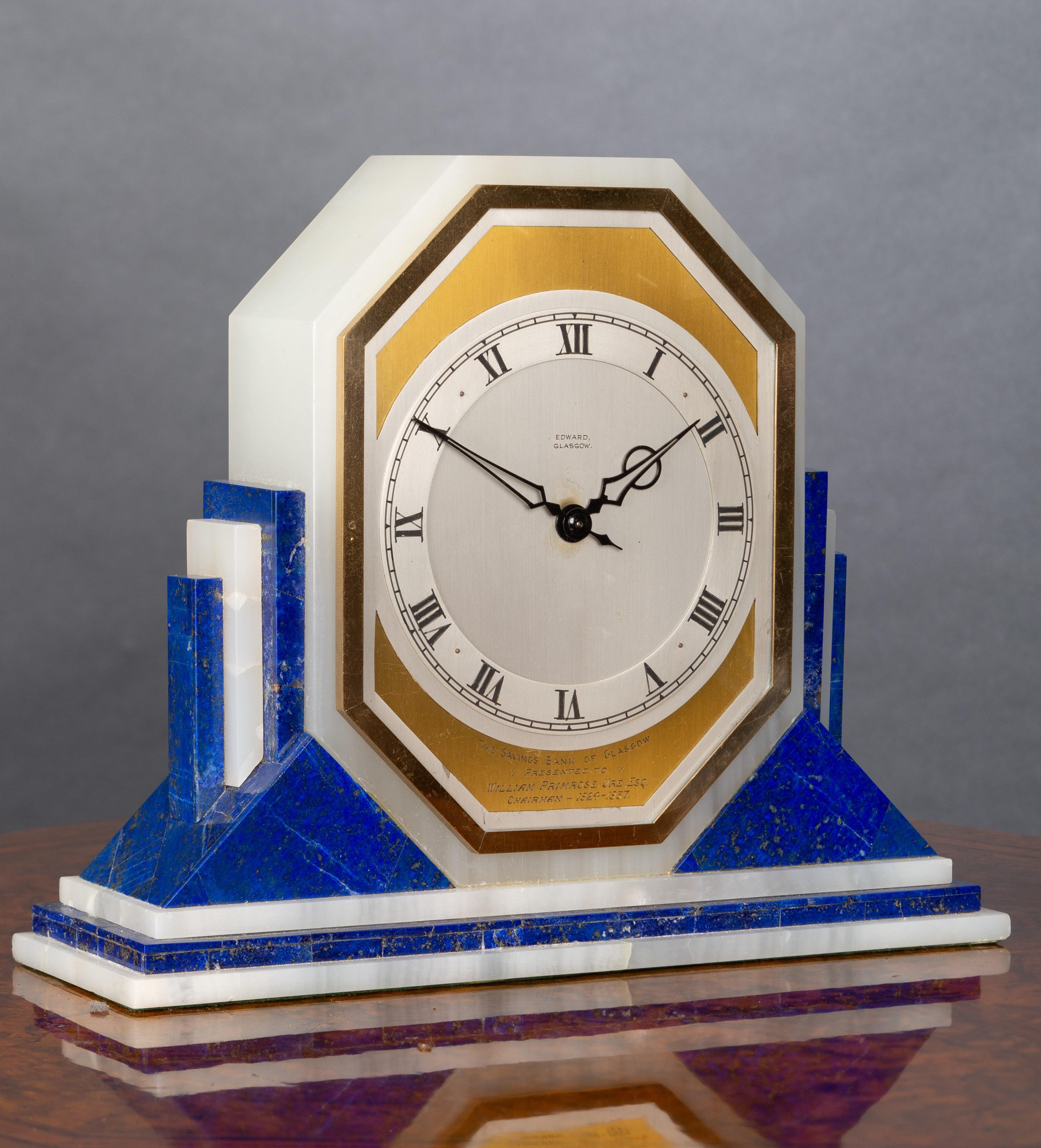 Art Deco mantel clock with a stepped base in Alabaster and Lapis Lazuli with similarly stepped sides.


Gilded dial mask surrounding a silvered centre signed ‘Edward, Glasgow’ with silvered chapter ring, Roman numerals and original ‘Deco’ style