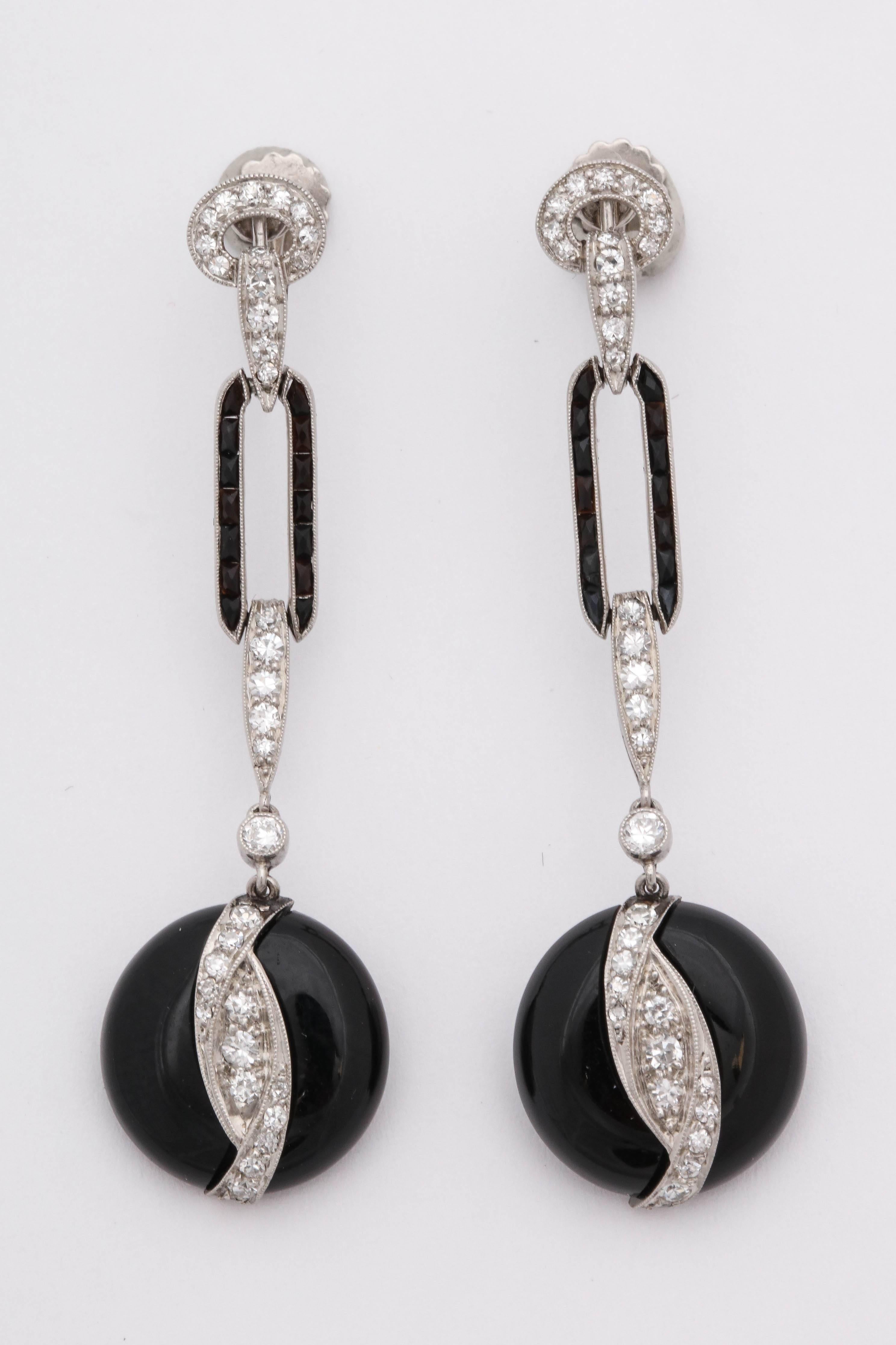 One Pair Of Platinum Screwback Earrings Designed With Numerous French Cut Onyxes In An Open Loop Setting And Further Embellished With Numerous Antique Cut Diamonds Weighing Approximately 2 Carats Total weight. A Custom Cut Circular Onyx Is Hanging