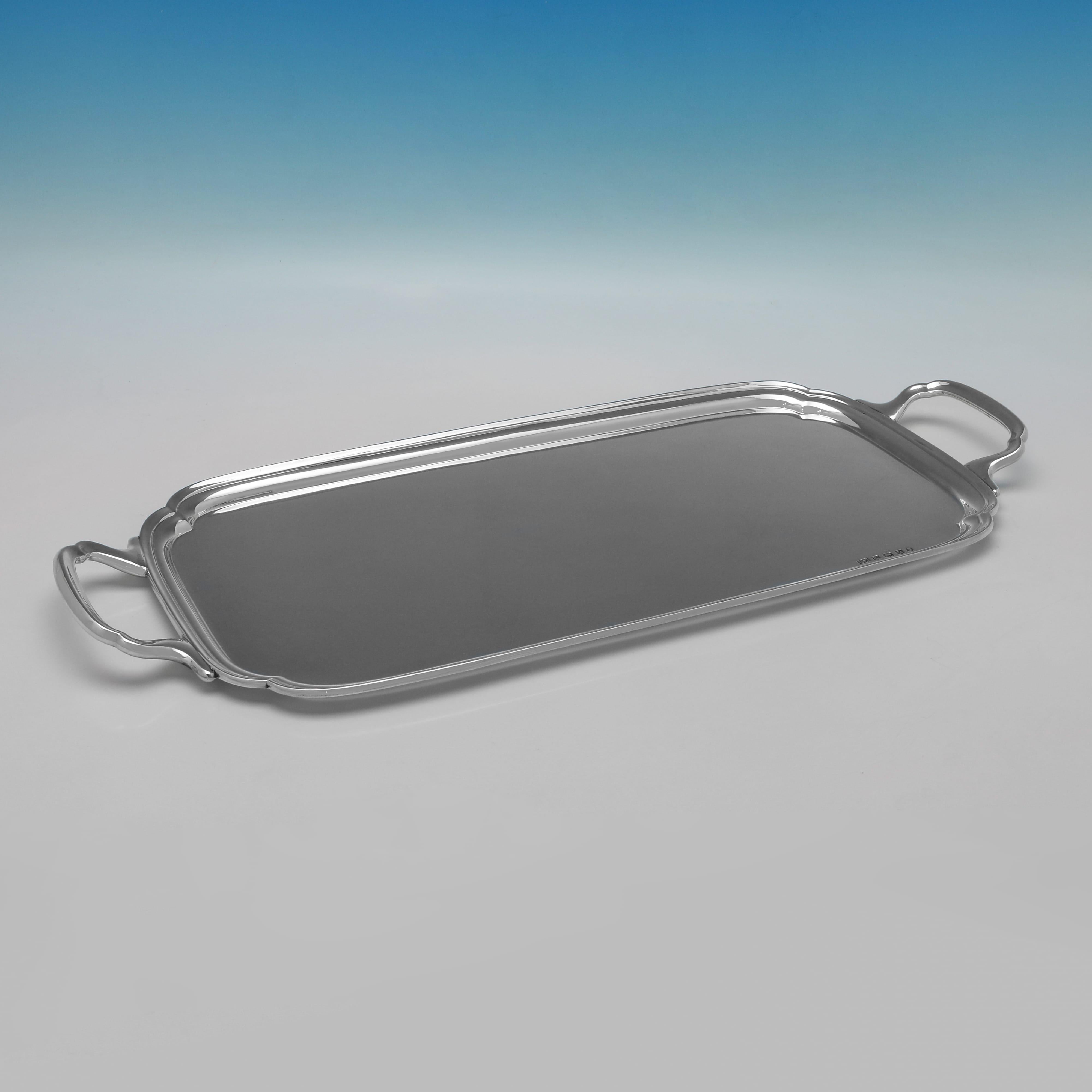 Hallmarked in Sheffield in 1934 by Viner's Ltd. this classic George V sterling silver bar tray is of a rectangular form with rounded corners, has a polished surface with a simple reeded border, and is fitted with a pair of plain angular handles. It