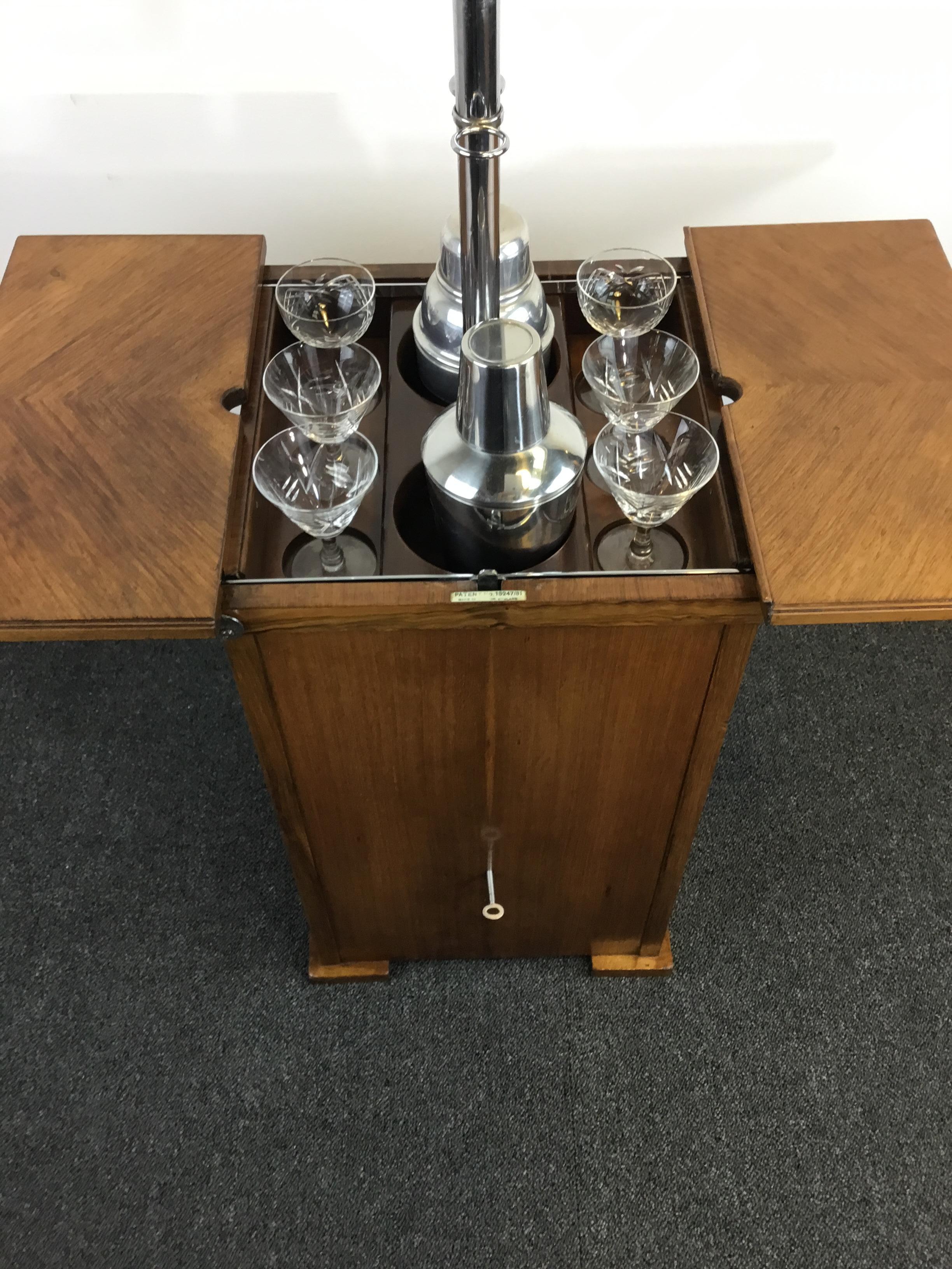 An Art Deco walnut ‘Elevette’ drinks cabinet, produced for Asprey London. British, circa 1930.
A very stylish piece of Art Deco furniture. 
A clever mechanism opens the top and lifts up a drink compartment, for six glasses and two bottles. 
It