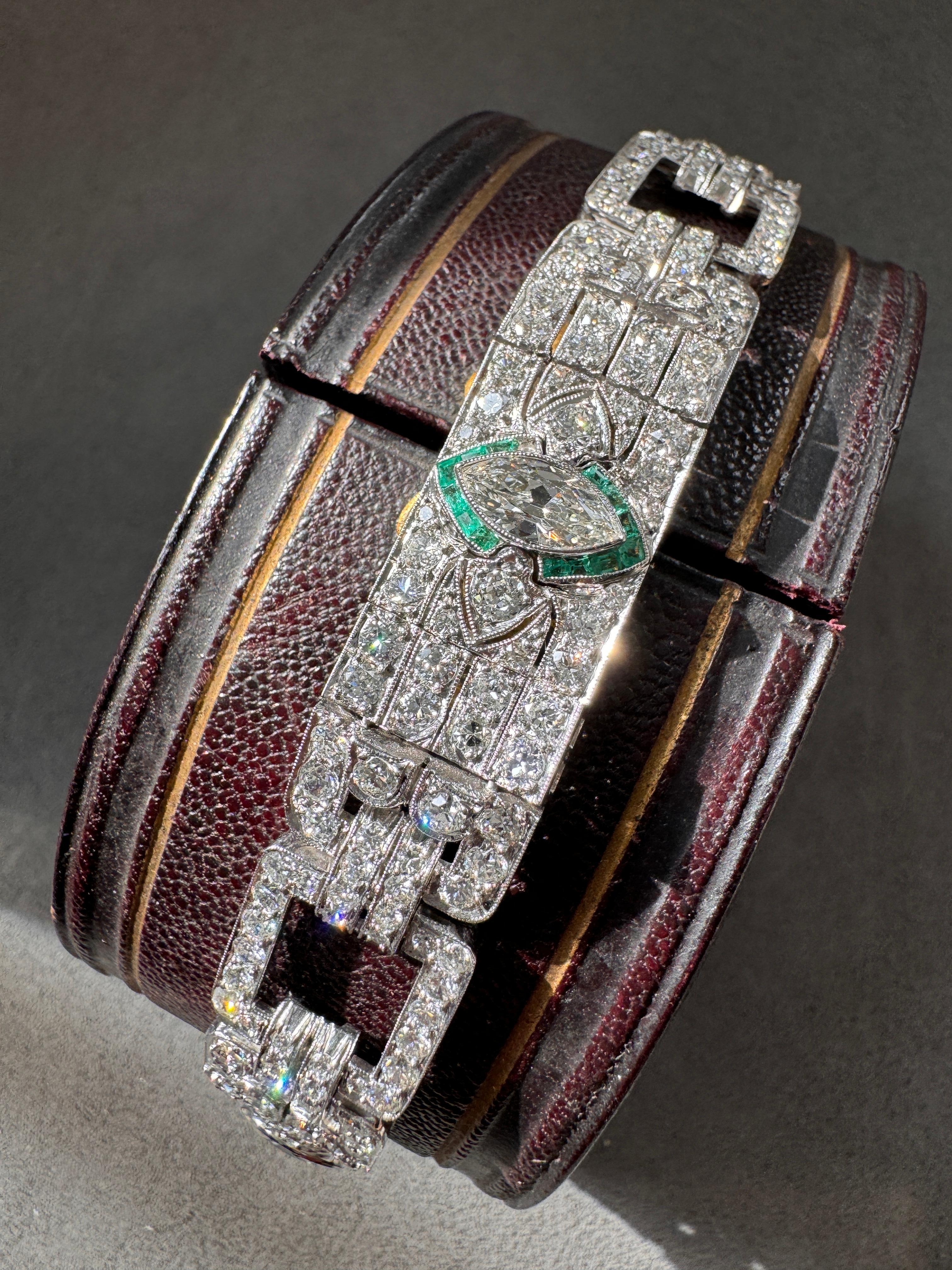 This sensational Art Deco bracelet is comprised of three segments, each centered by an old marquise-cut diamond outlined in glowing calibre emeralds, accented on each side by full-cut diamond centered arrows. Each glistening diamond plaque is joined