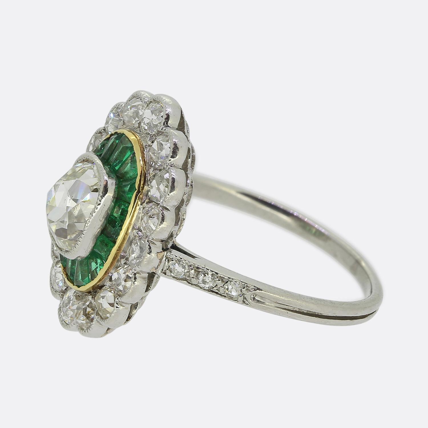 Hier haben wir einen auffälligen Cluster-Ring, der während der Art-déco-Bewegung gefertigt wurde und eine harmonische Mischung aus Diamanten und Smaragden zeigt. Sein Herzstück ist ein länglicher, rechteckiger Diamant im alten Kissenschliff, der