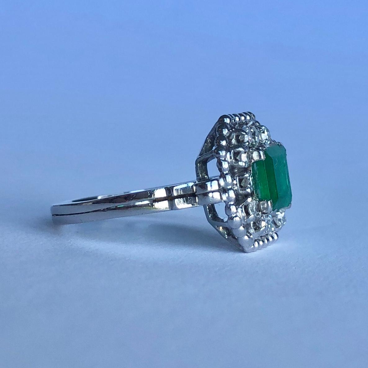 At the centre of the sparkling halo of diamonds and platinum beaded frame is a beautiful size emerald. The diamonds total approx 50pts and the classic square cut emerald measures approx 1.3carats. Modelled in platinum. 

Ring Size: N or 6 3/4