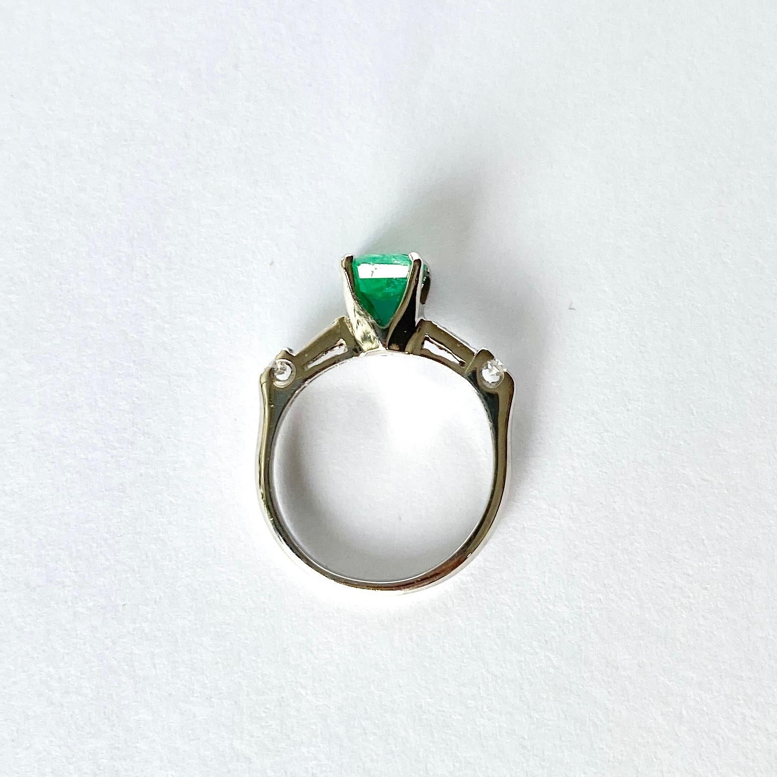 The Emerald in this ring measures 1ct and is a great colour. Either side sit a baguette and round diamond on the shoulders. The diamond total of the ring is 20pts. The ring is modelled in platinum. 

Ring Size: H or 3 3/4 
Height Off Finger: