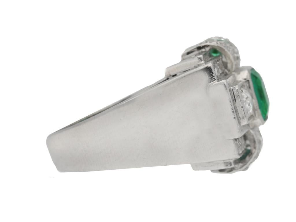 Art-Deco-Ring mit Smaragd und Diamanten. In der Mitte ein achteckiger natürlicher Muzo-Smaragd im Smaragdschliff in einer offenen Rubover-Fassung mit einem Gewicht von 0,90 Karat, oben und unten flankiert von zwei achteckigen natürlichen Smaragden