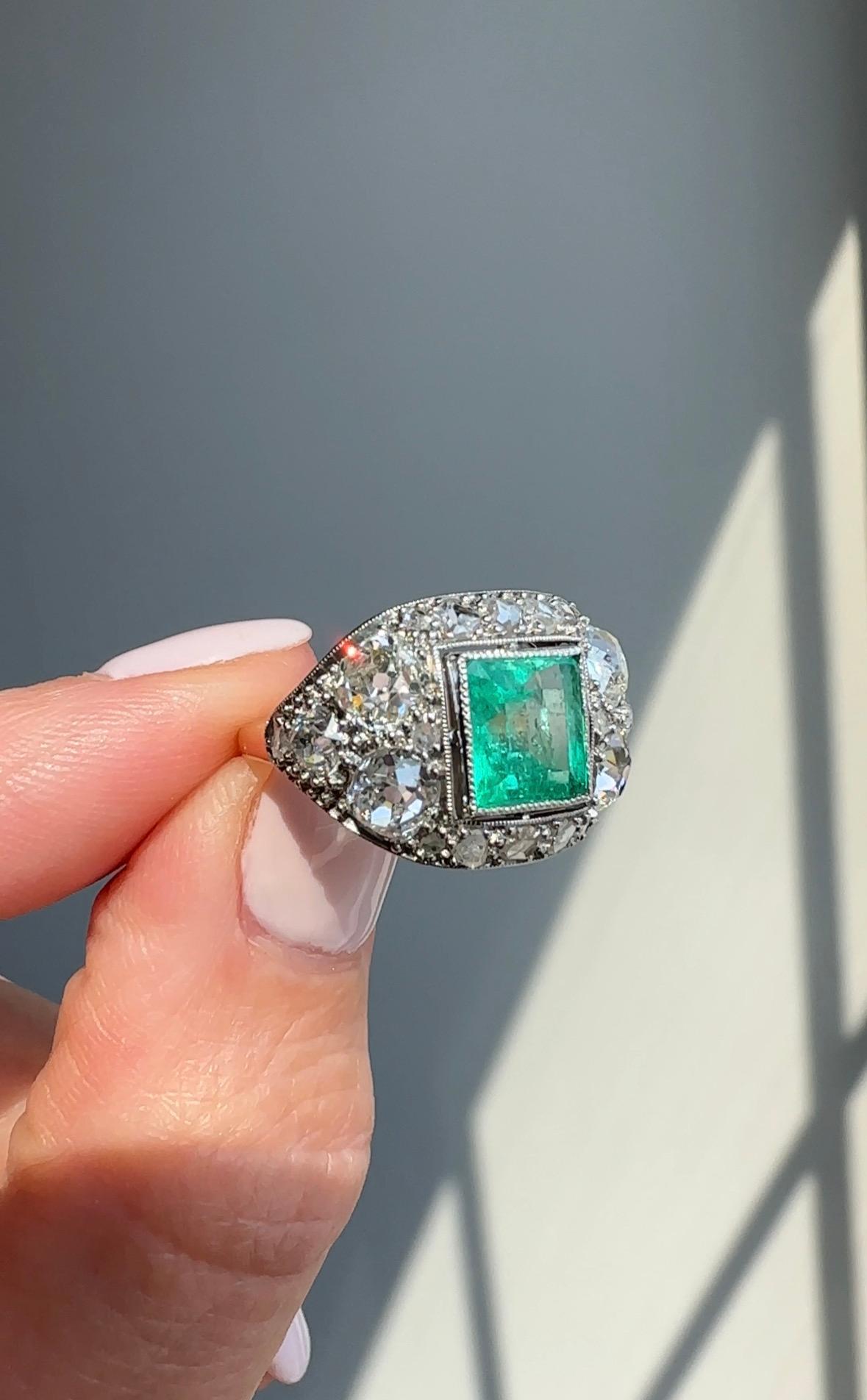 This stunning finger hugging Art Deco ring centers on a gemmy square-shaped Colombian emerald, weighing 1.7 carats, that glows from within 1.65 carats of chunky old mine cut diamonds, set in platinum and 18K yellow gold. Exceptionally lovely. This