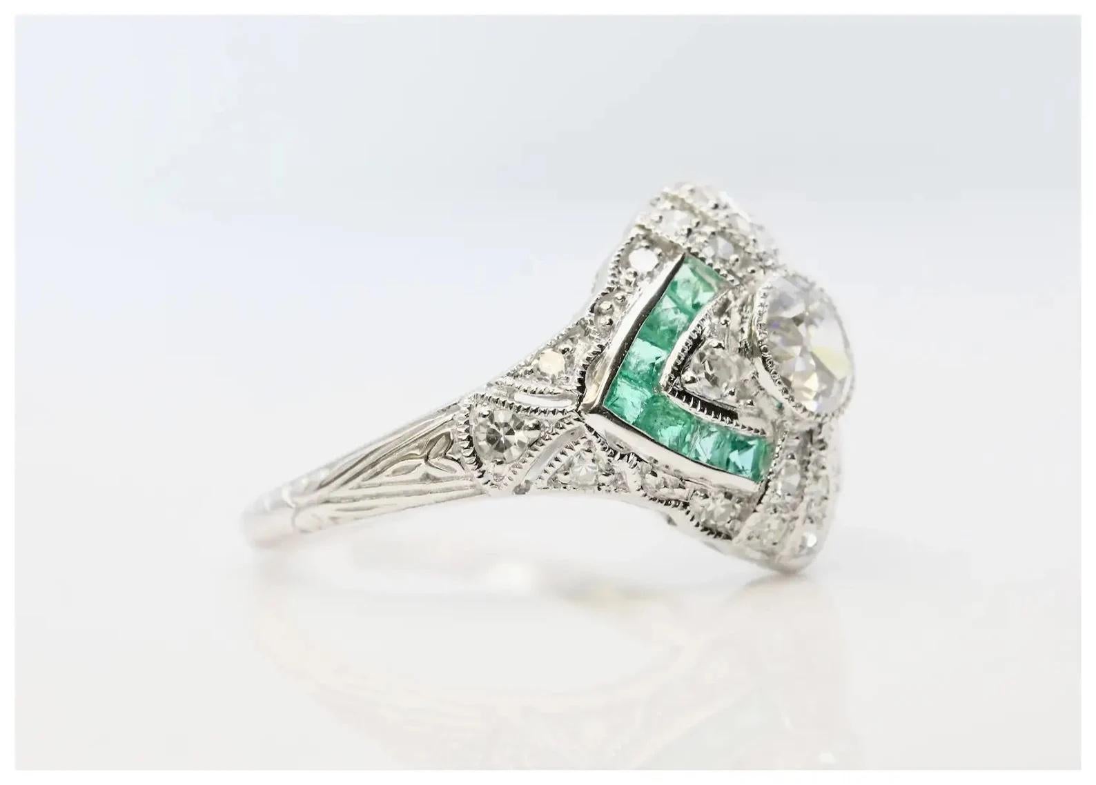 An Art Deco style diamond, and emerald ring crafted in 14 karat white gold.

Centered by a 0.50 carat old European cut diamond of H color, VS2 clarity.

Framed by fourteen French cut emeralds of vivid green color and twenty four pave set