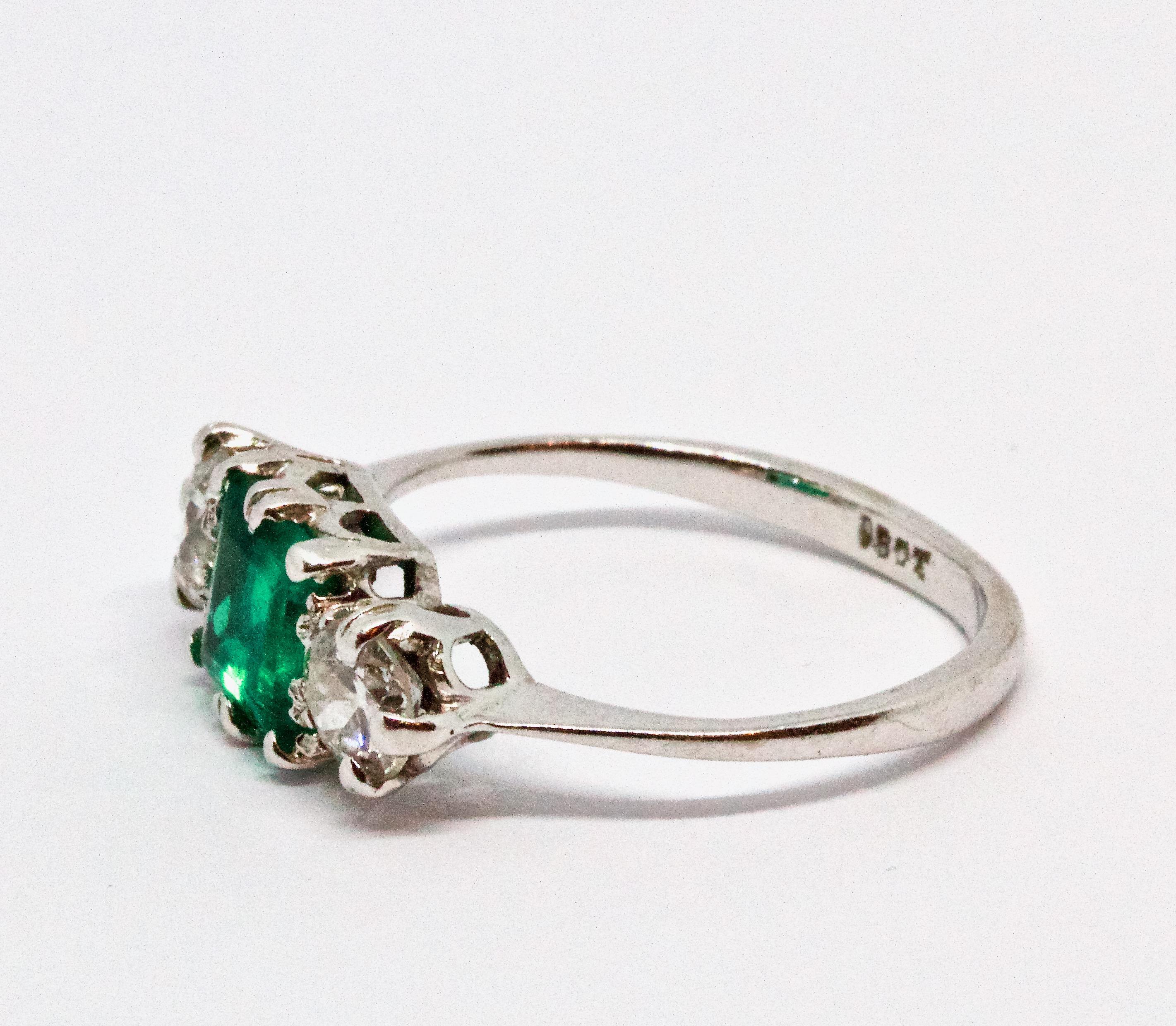 A mesmerising Art Deco era Emerald and Diamond trinity ring. The principal stone (claw set) displays an excellent deep green colour, and the two flanking quarter carat Old European cut diamonds are bright and clean with an G colour and SI-1 clarity.