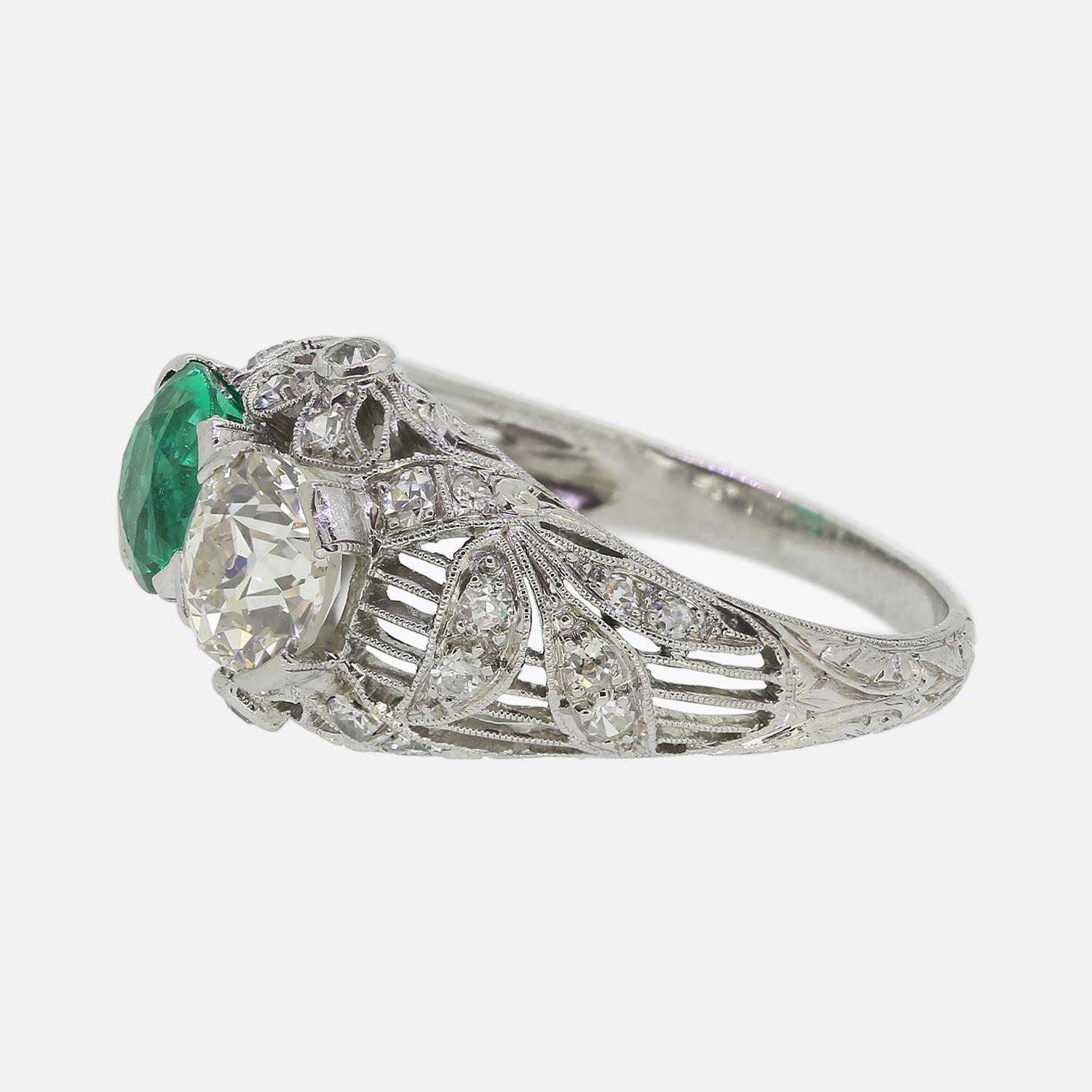 Here we have an exquisite two-stone ring crafted from platinum during the Art Deco movement. This characterful piece features a harmonious pairing of precious gemstones at the centre of the face. On one side we find a round faceted emerald radiating
