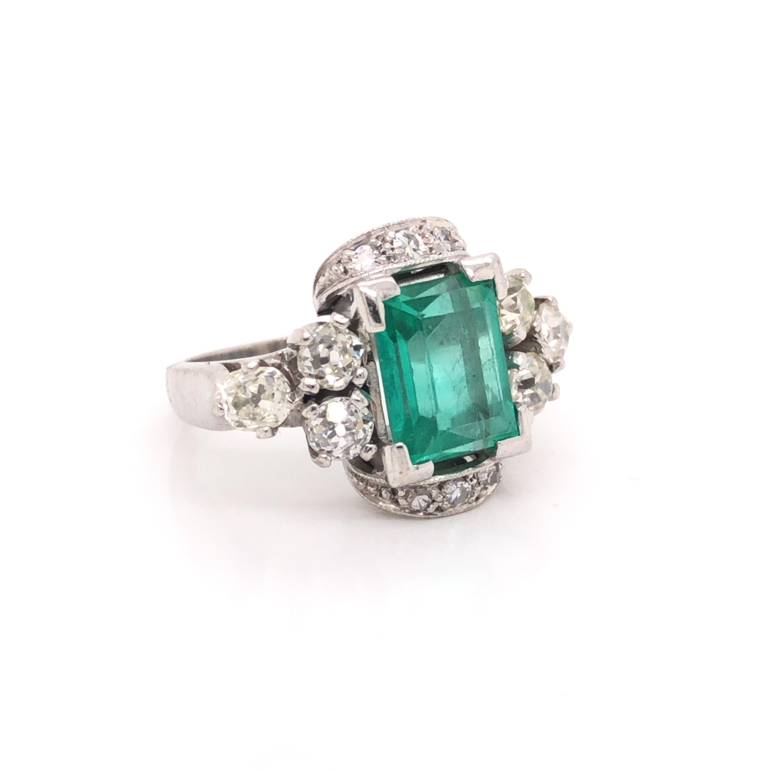 Gorgeous ring crafted in 18k white gold. This fine Art Deco period ring is a real show stopper. The ring is highlighted with one emerald gemstone that displays an emerald cut and shows a beautiful green color. The center stone is adorned with old