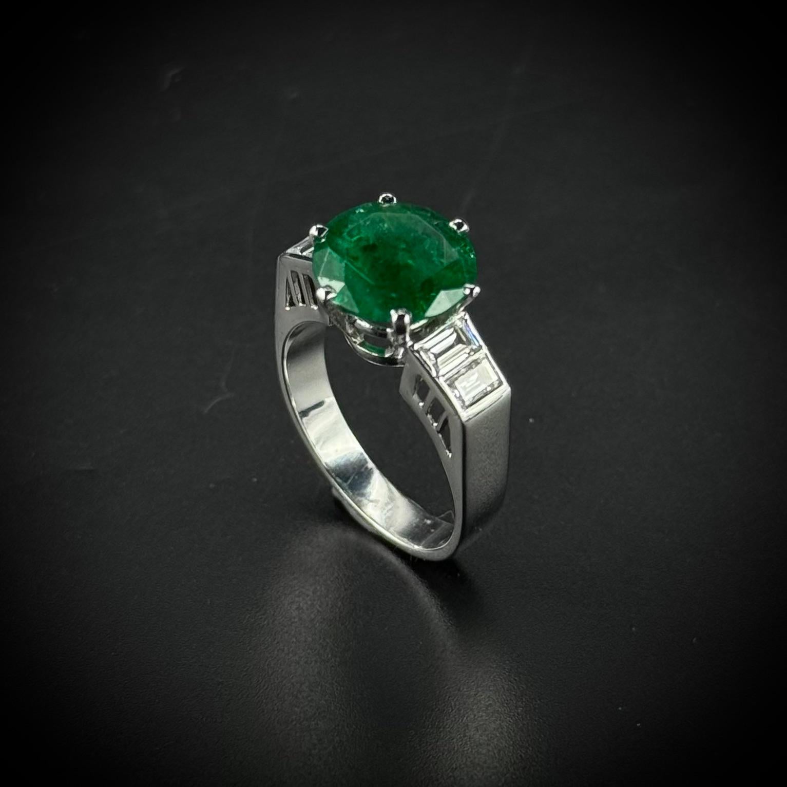 Anillo de compromiso Art Déco de esmeralda y diamantes en platino, del orfebre portugués Carlos Joaquim Xavier, años 40/50. Esta joya presenta una esmeralda circular verde vibrante de aproximadamente 2,93 quilates, engastada en una segura montura de