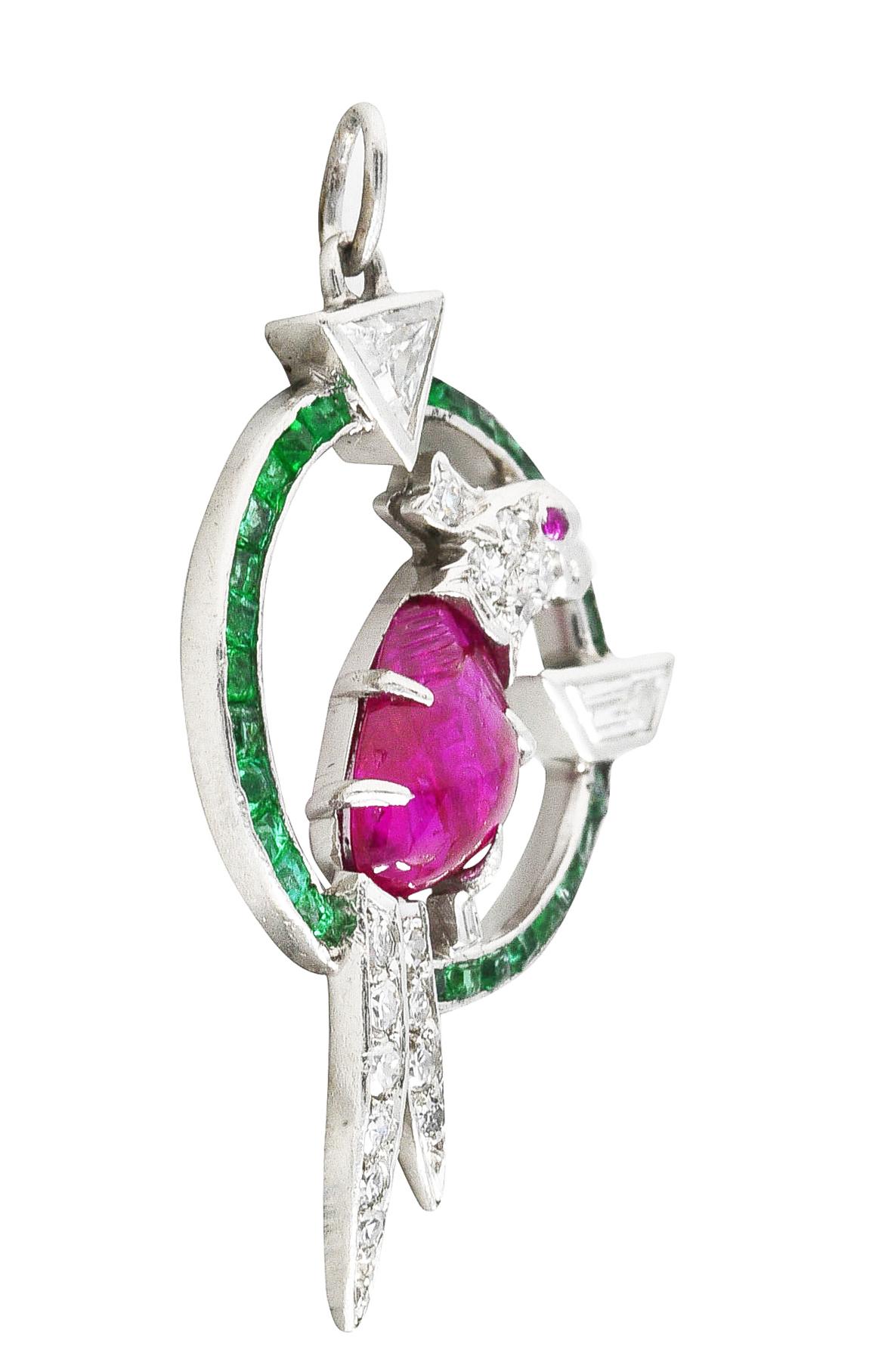 Circular charm features a perched cockatiel bird. Eye is a ruby cabochon matched to its Mughal carved cabochon ruby body. Surrounded by a halo of channel set calibrè cut emeralds - approximately 0.50 carat total. Well matched and bright green with