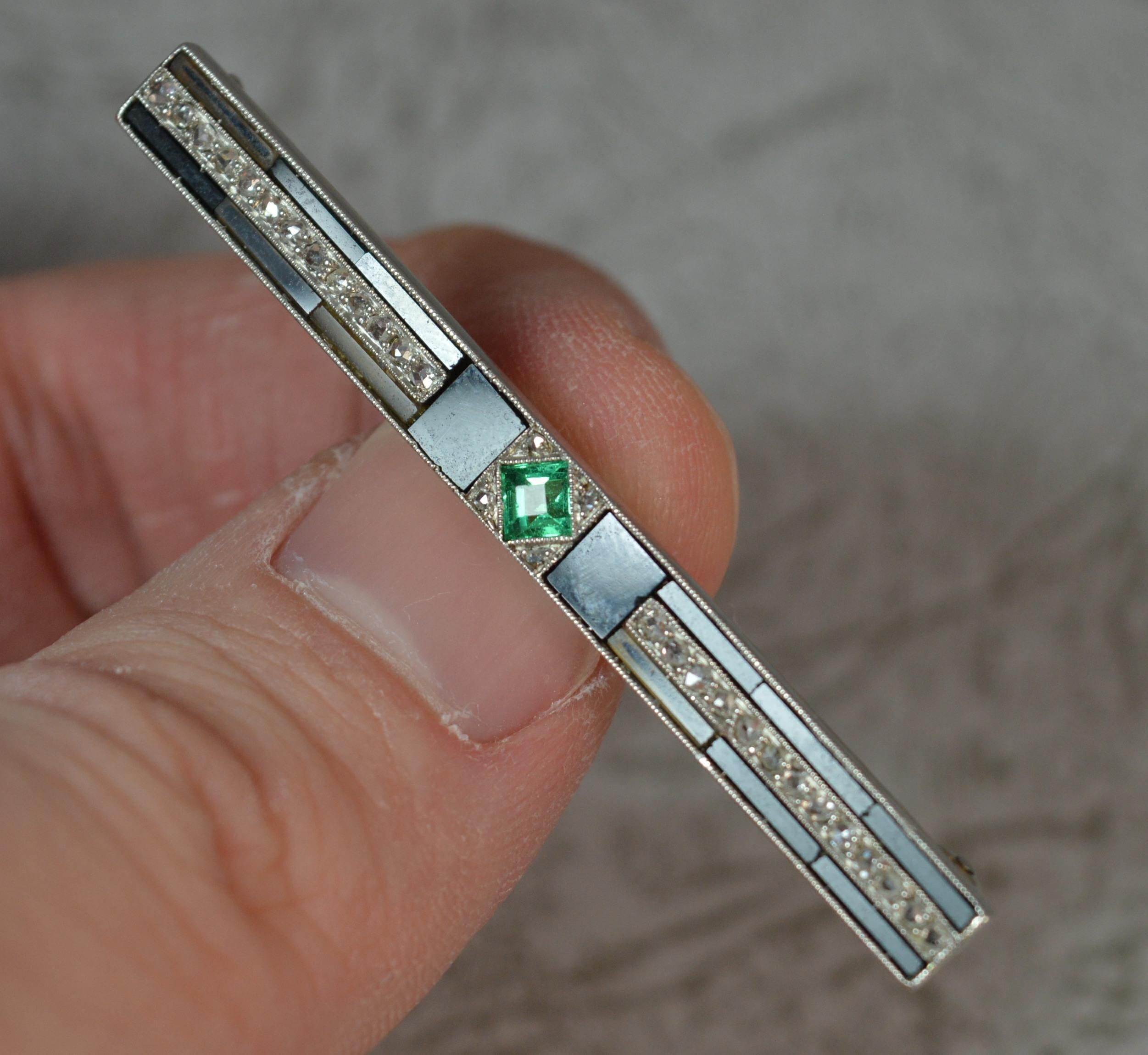 A fantastic Art Deco era bar brooch.
Modelled in platinum throughout.
Designed with a Colombian emerald of princess cut to centre. A small diamond to each side. The sides are then set with multiple pieces of black onyx and further rose cut