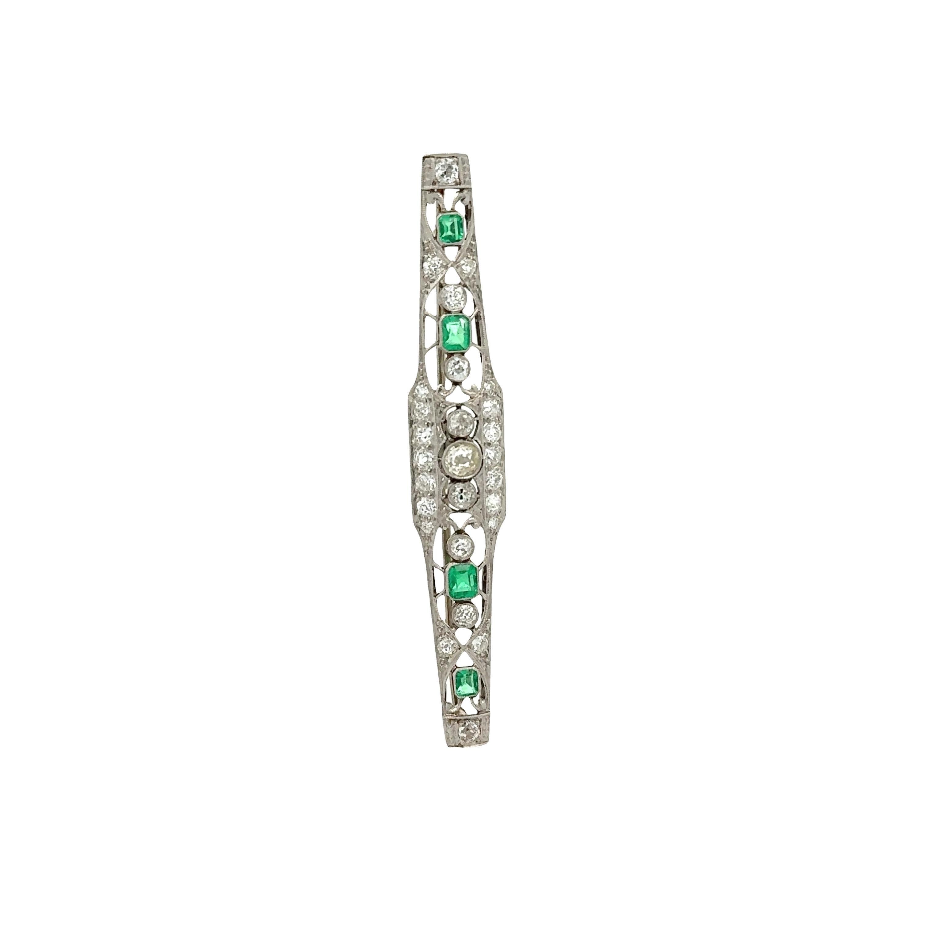 Elegante broche de finales de la década de 1920 que exhibe vibrantes esmeraldas verdes y deslumbrantes diamantes blancos. Las esmeraldas están talladas en la clásica forma de esmeralda, con un peso total de 1 quilate, y están engastadas en medio de