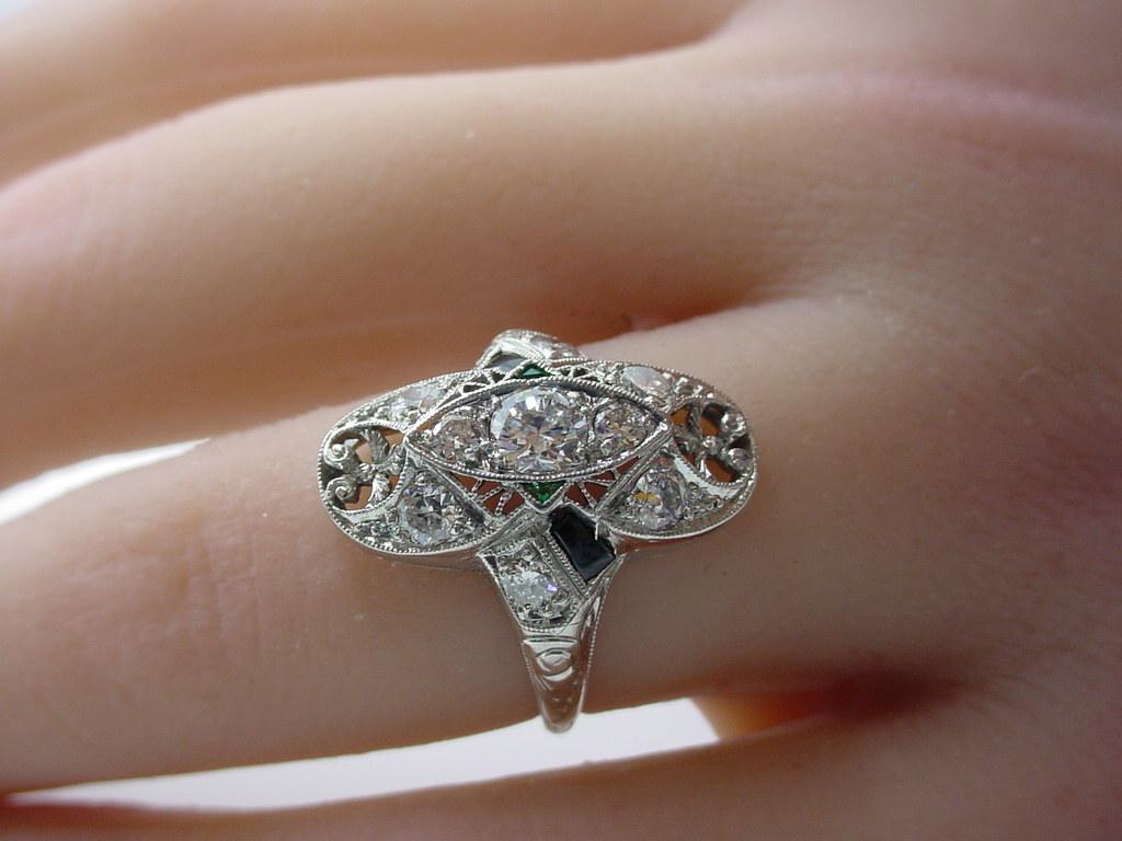 Stunning authentic Art Deco ring rendered n luxurious platinum... 

An Art Deco diamond, emerald, onyx and platinum ring, the navette form design, featuring 7 old European-cut diamonds, further accented by onyx and emerald, between old European-cut