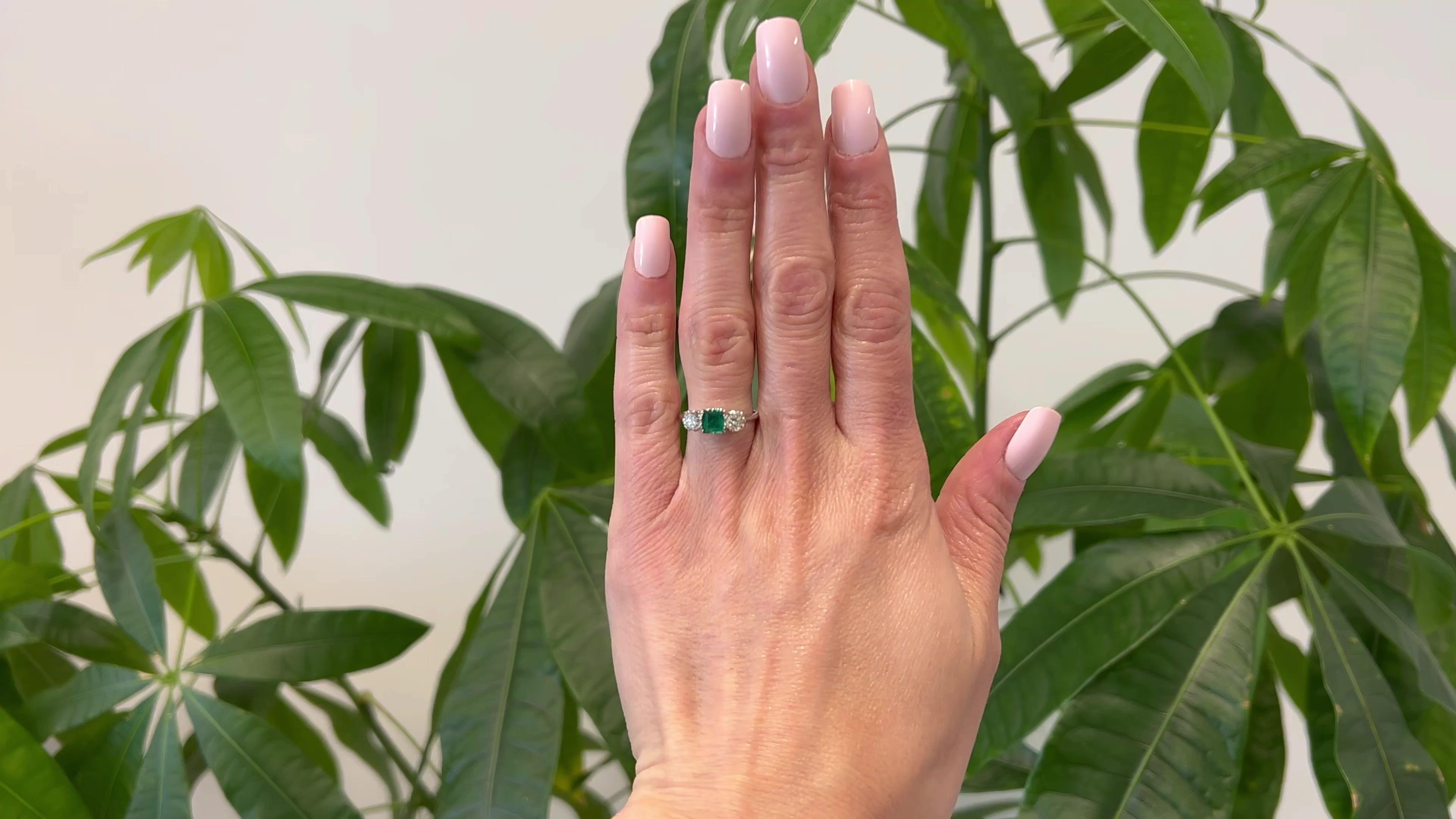 One Art Deco Emerald Diamond Platinum Three Stone Ring. Featuring one rectangular step cut emerald weighing approximately 0.60 carat. Accented by one old European and one round brilliant cut diamond with a total weight of approximately 0.75 carat,