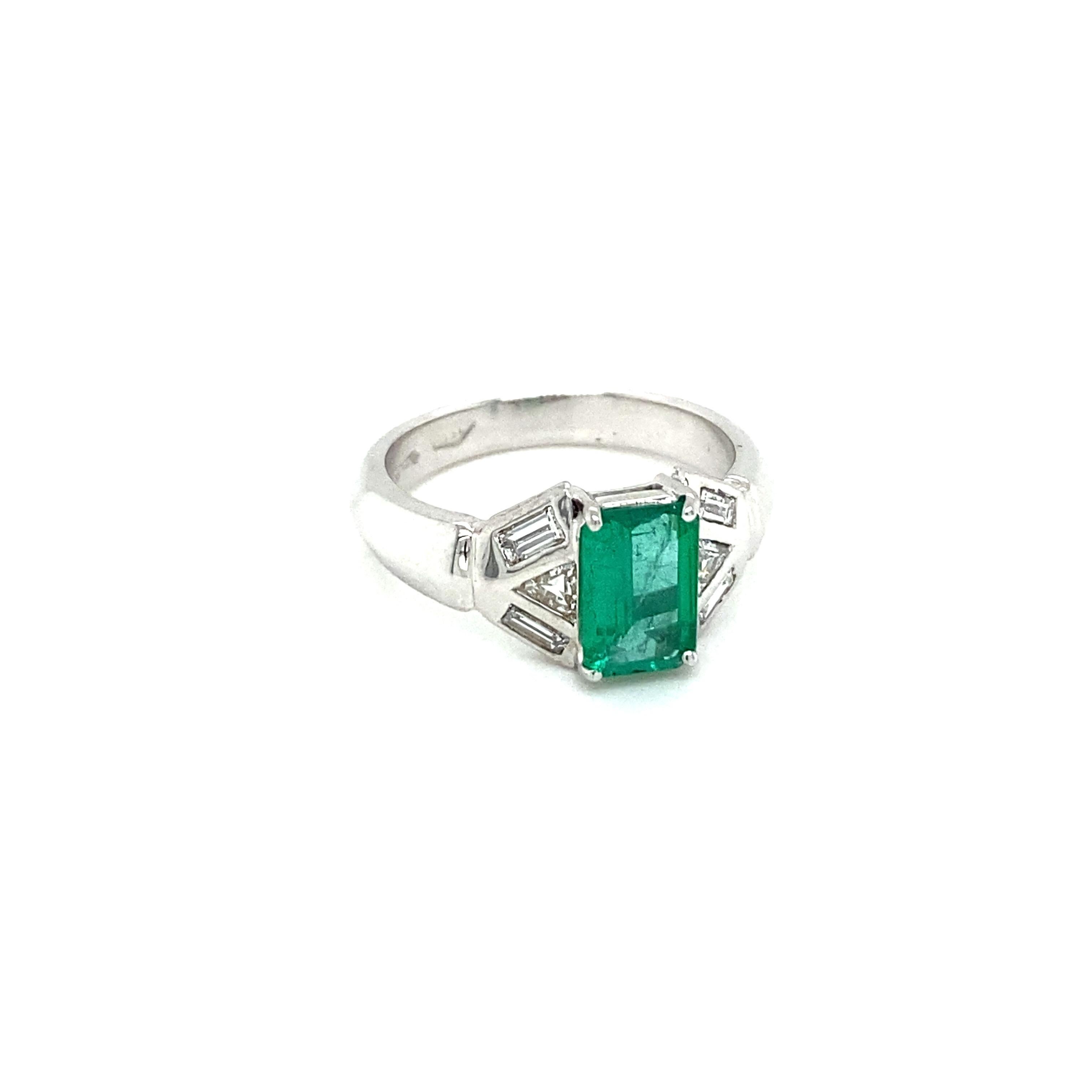 An Art Deco Emerald and diamond ring handcrafted in 18k gold. The ring is set with one beautiful emerald cut 1.04 ct Natural Emerald framed by six baguette cut diamonds and two Trillion diamonds. Circa 1930

CONDITION: Pre-Owned - Excellent 
METAL: